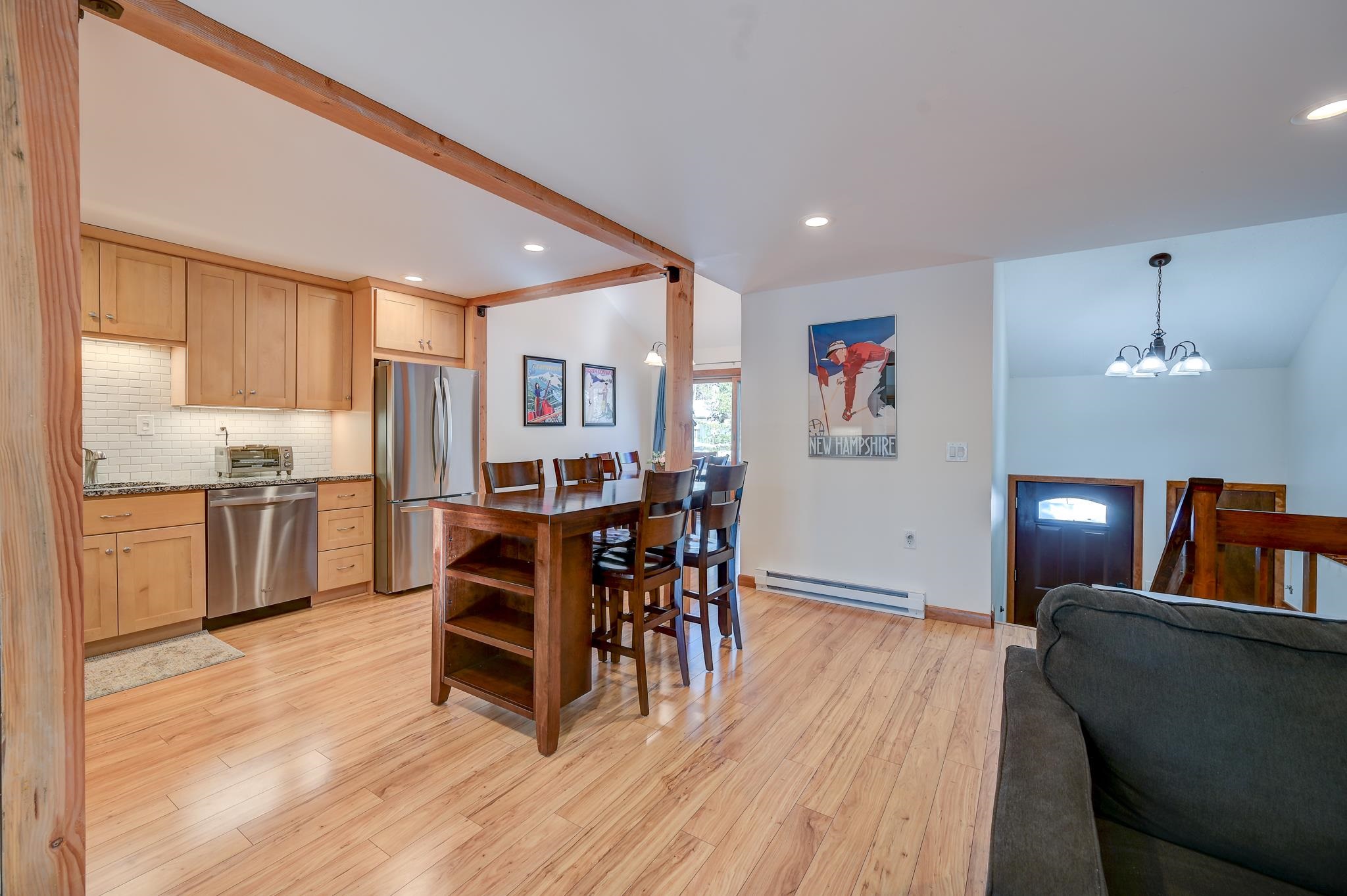 Open-plan kitchen and dining area with light wood cabinets, stainless steel appliances, and exposed timber beams.