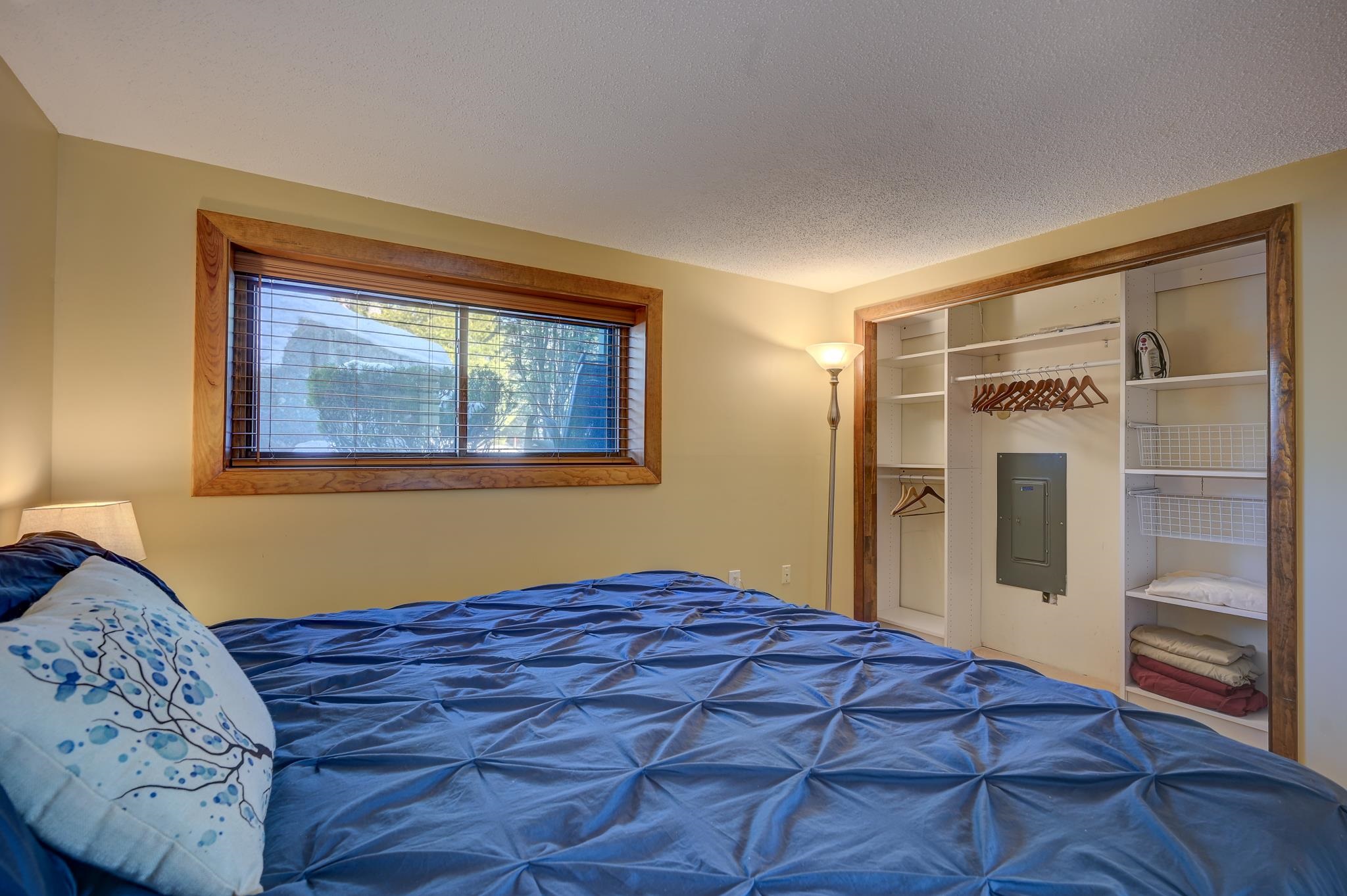 Bedroom with blue bedding, a wood-trimmed window, and an open built-in closet.