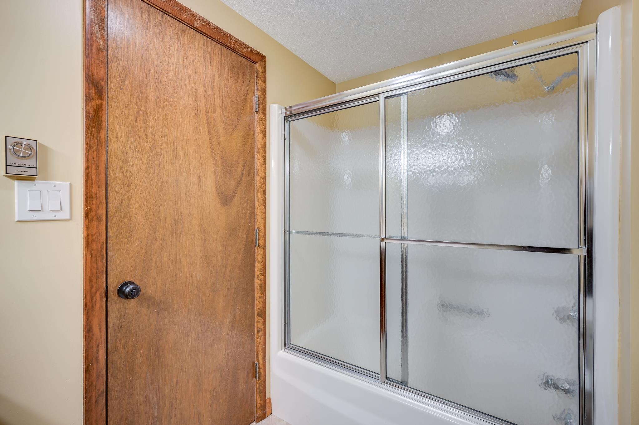 Bathroom shower with frosted-glass sliding doors beside a wooden door.