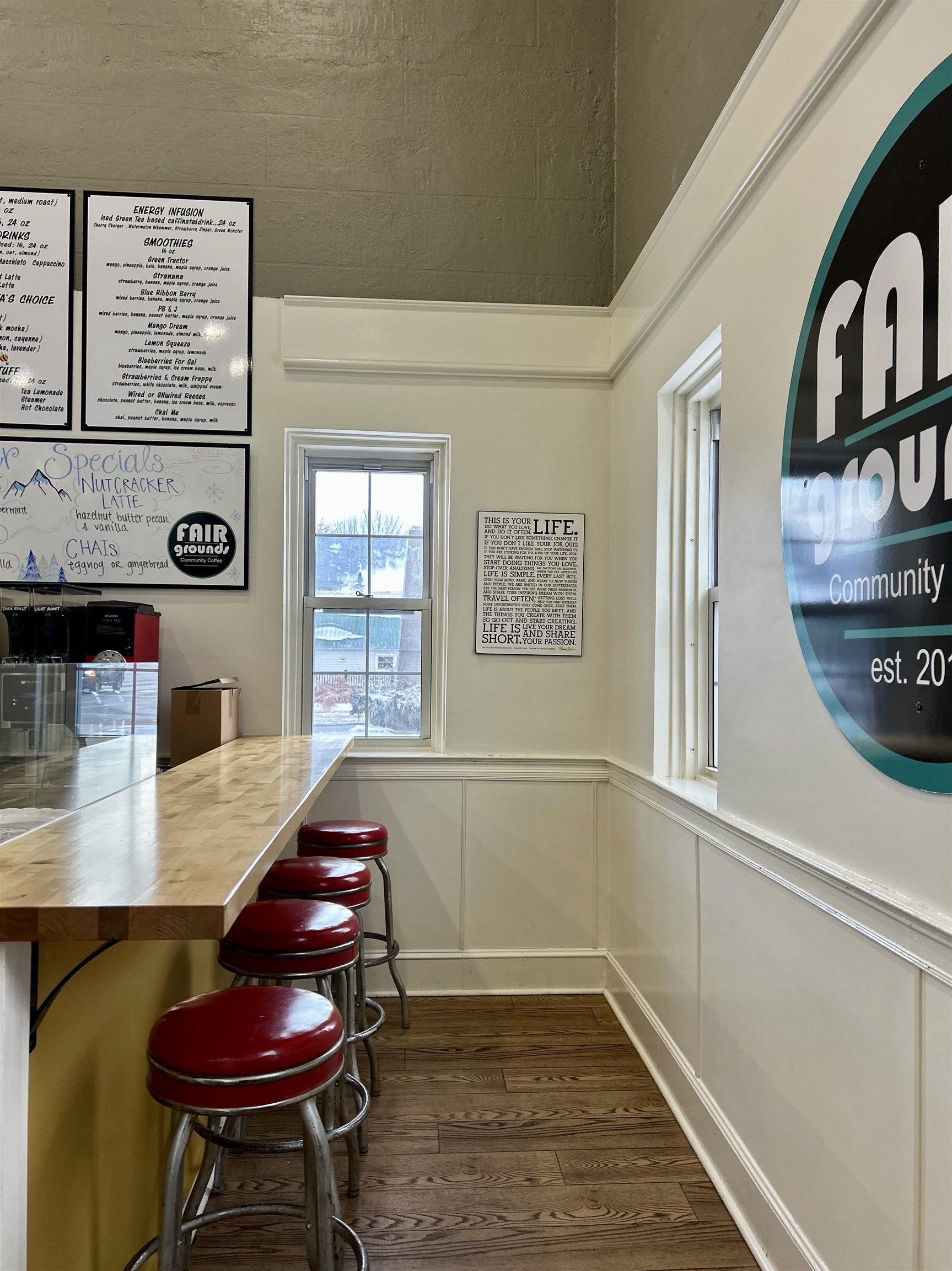 Coffee shop counter with red stools, menu boards, and a large Fair Grounds Community Coffee sign.
