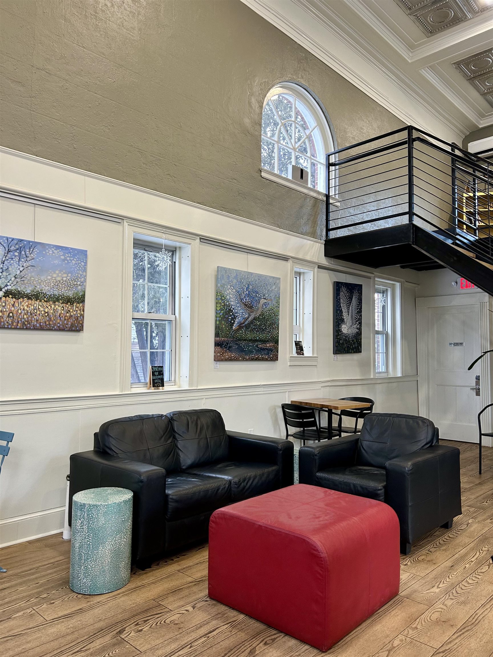 Interior seating area with black leather sofas, a red ottoman, and an elevated balcony.