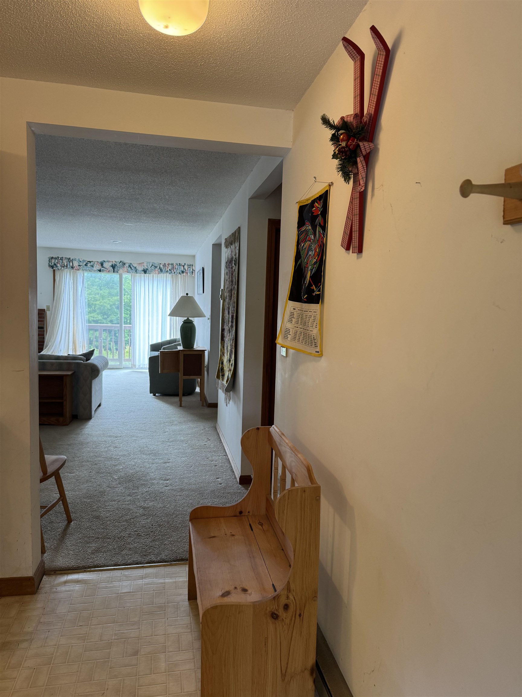 Condo entry hall with a wooden bench opening to a living room and sliding glass door.