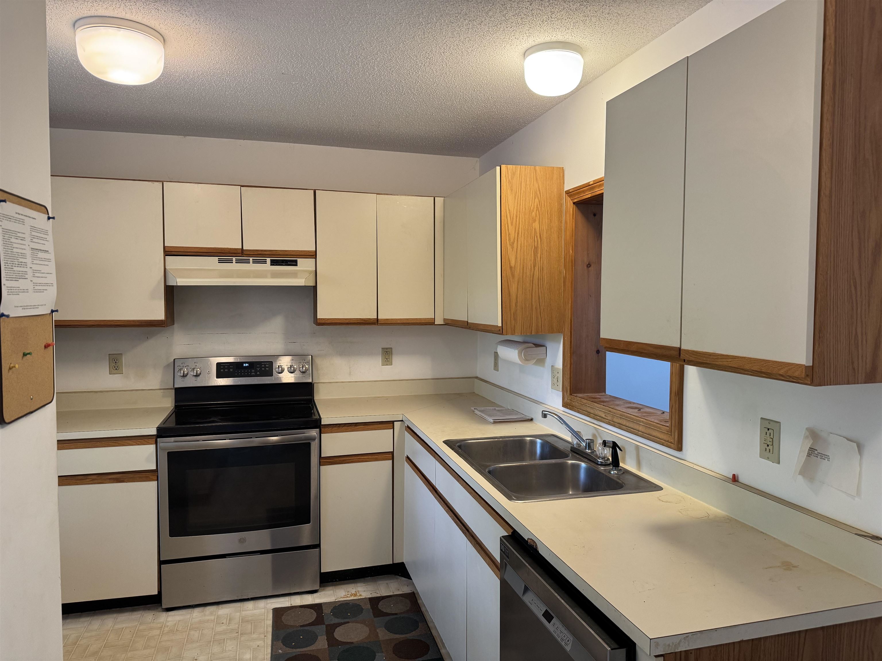 Kitchen with cream wood-trimmed cabinets, stainless steel range, double sink, and dishwasher.