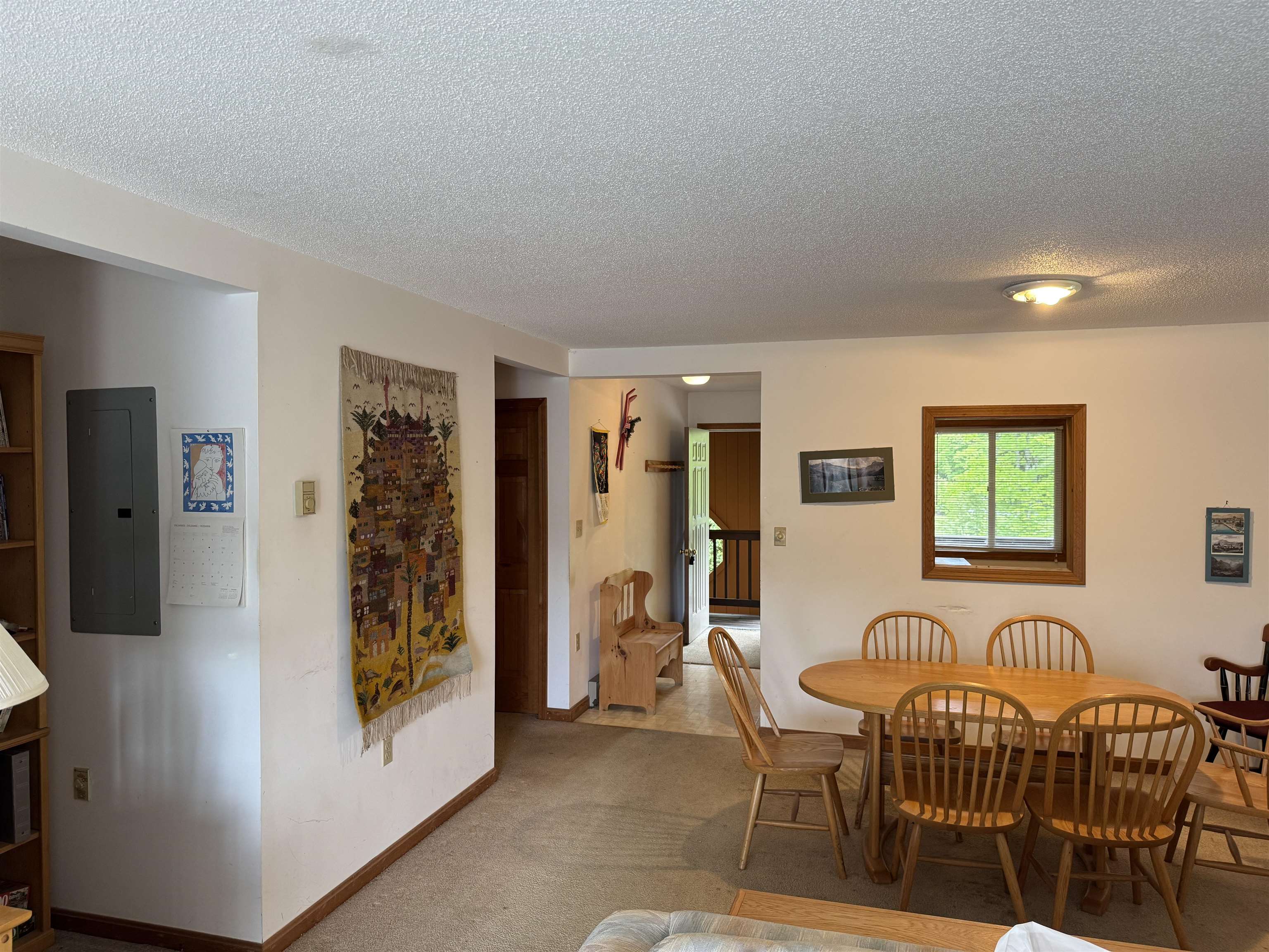 Dining area with a wooden table and chairs beside a window and open entryway.