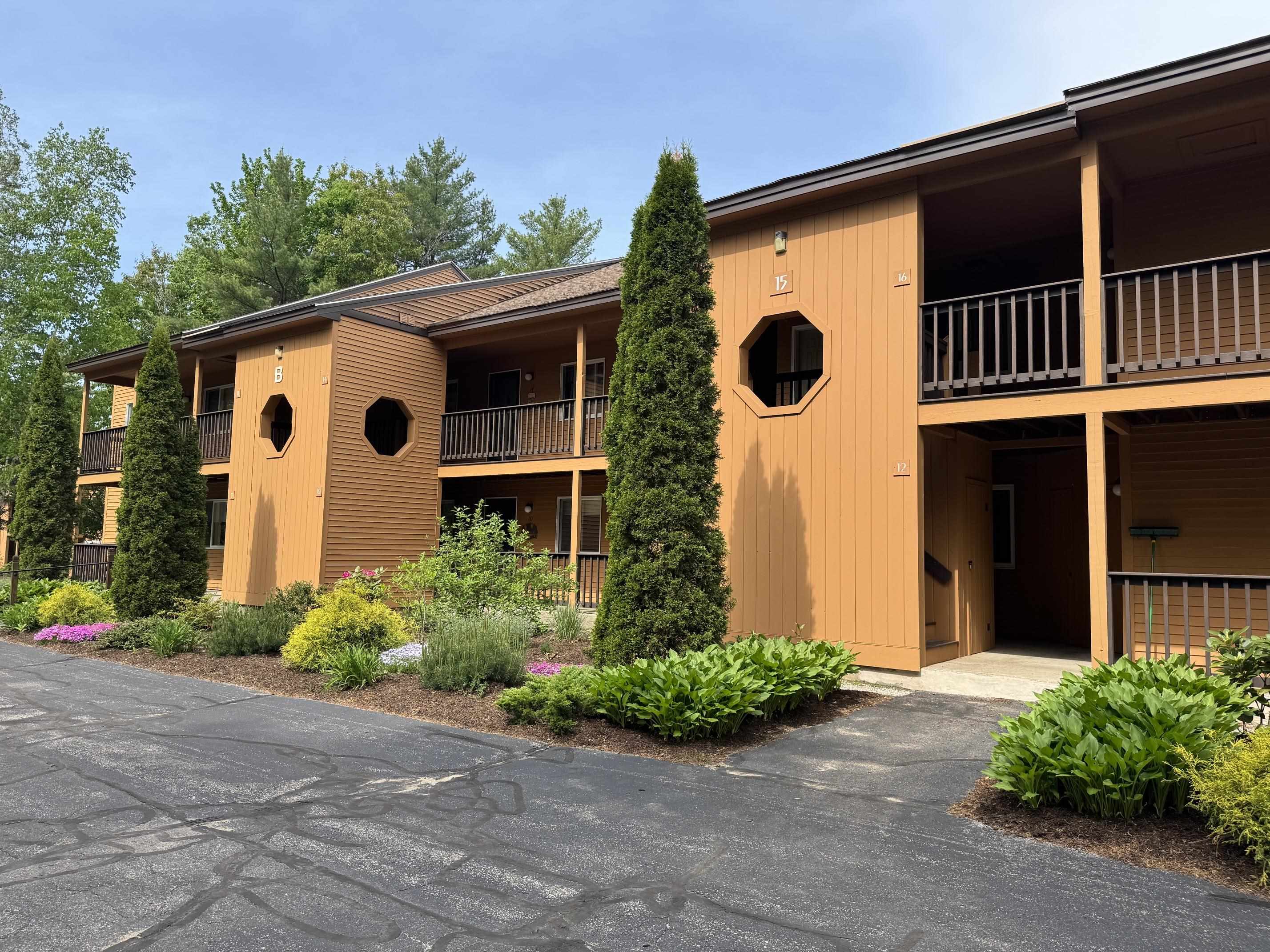 Orange-brown condominium building with covered balconies, octagonal windows, and landscaped grounds.