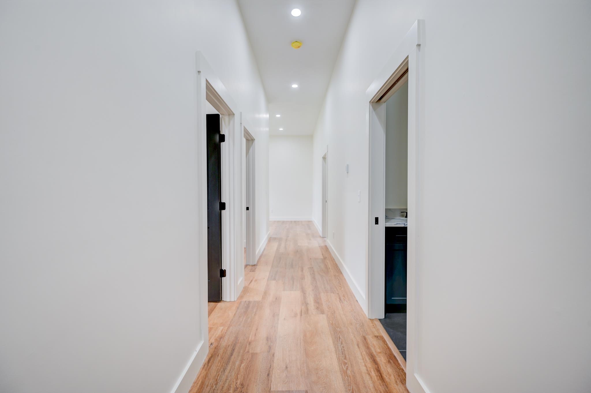 Unfurnished hallway with light wood-look flooring and recessed ceiling lights