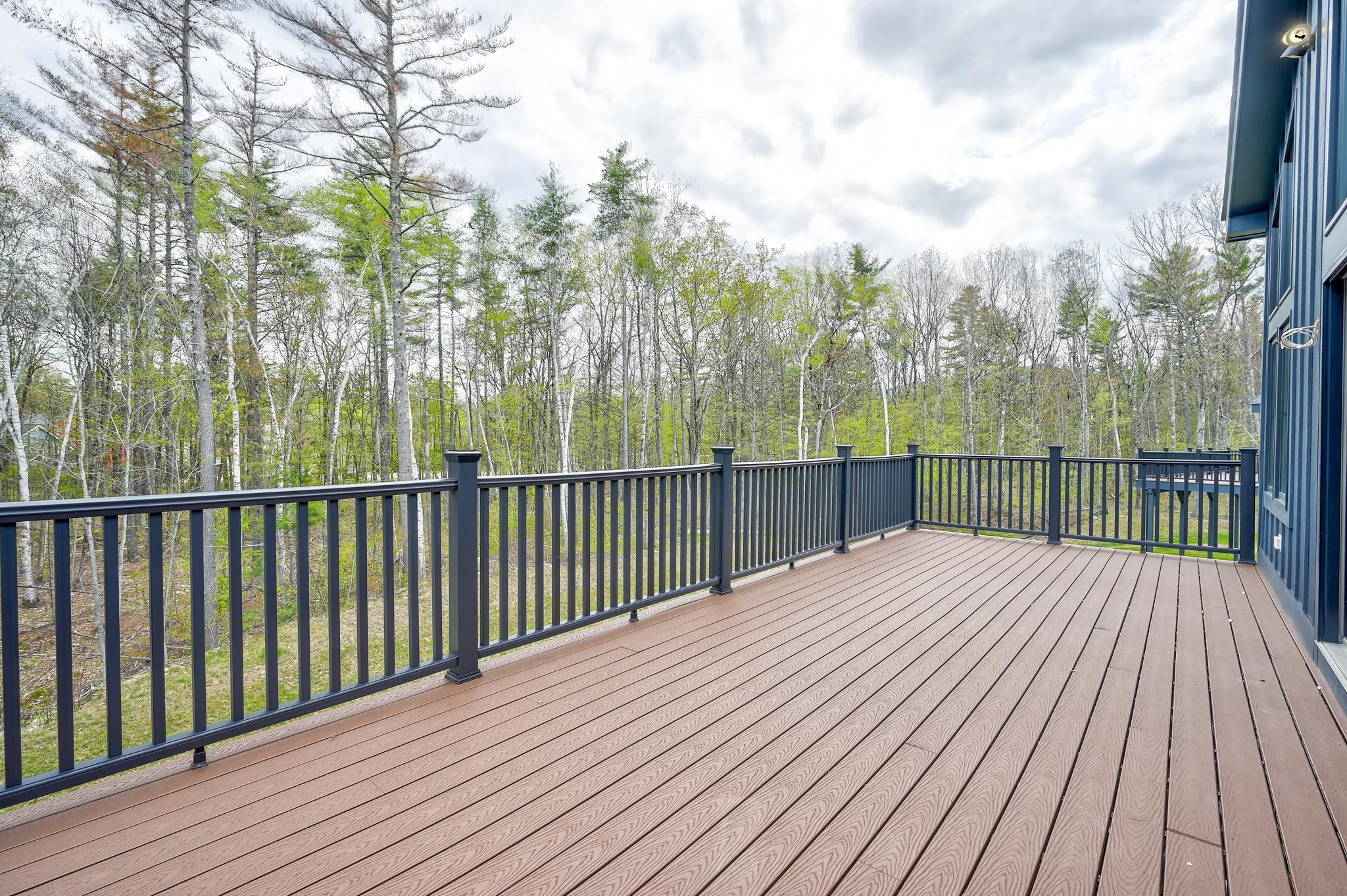 Spacious composite deck overlooking spring woodland, with dark railings beside blue siding.