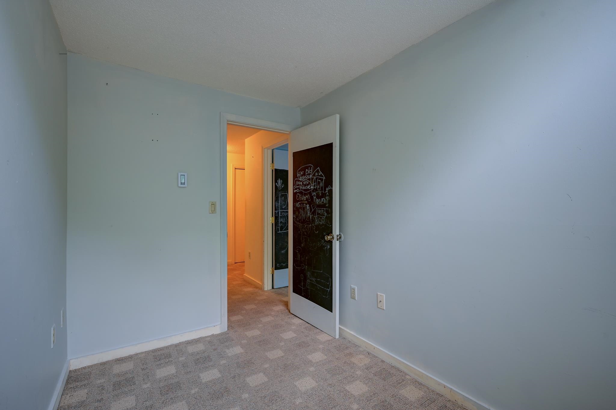 Empty bedroom with patterned carpet and an open chalkboard door.