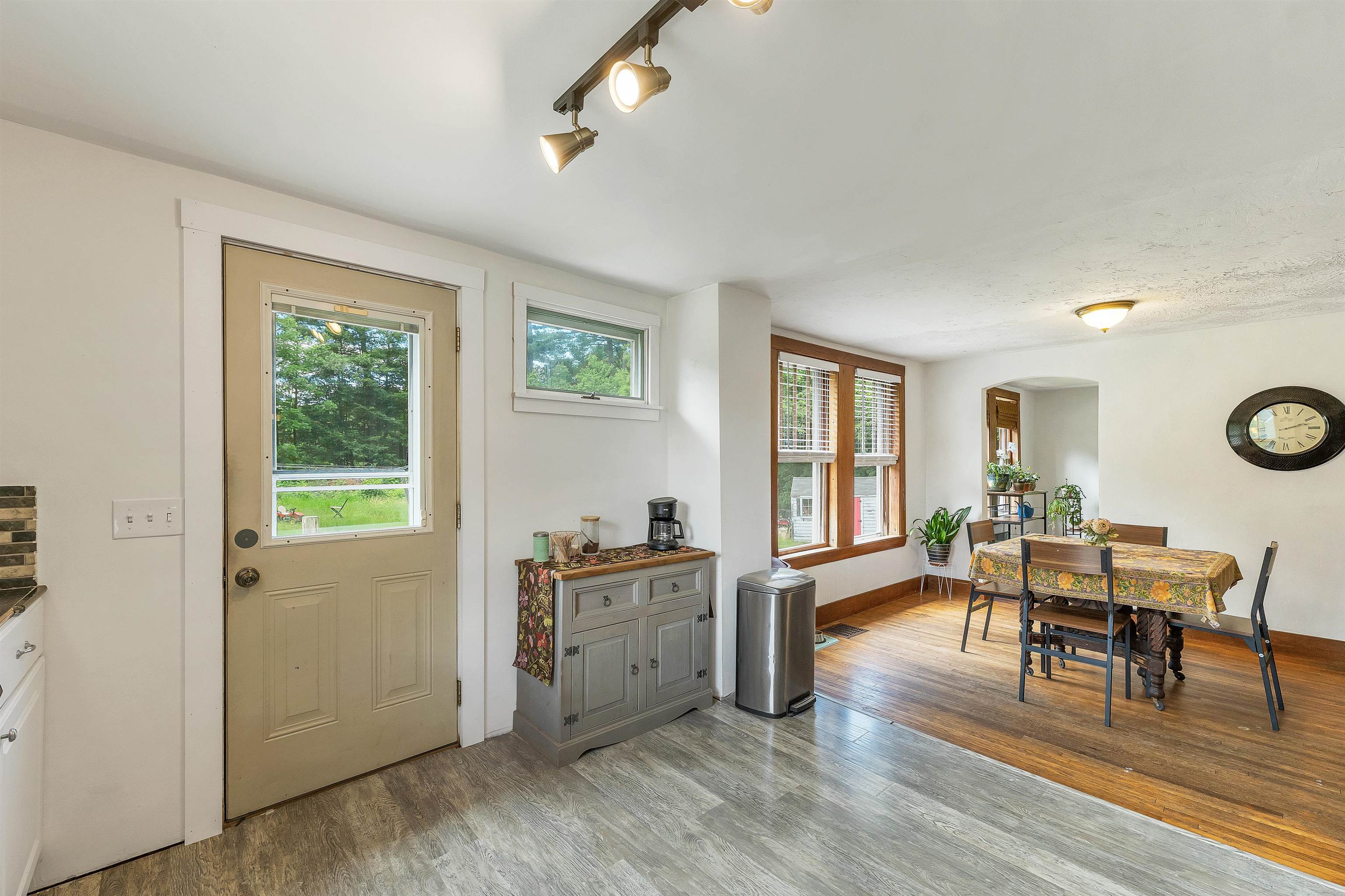 Dining area with a wooden table, large windows, and a glass-paneled entry door.