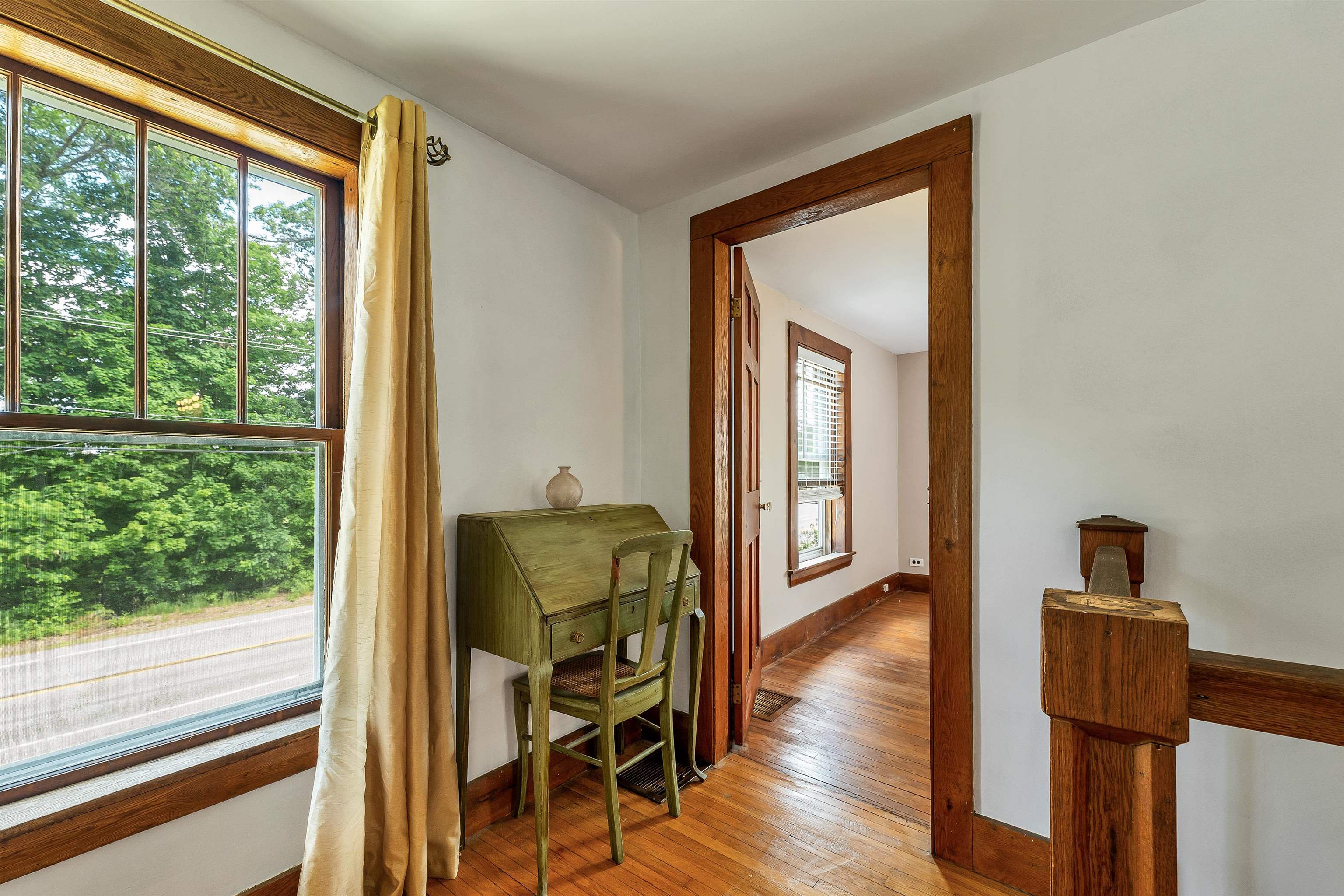 Furnished landing with a green desk beside a large window and a wood-trimmed doorway.