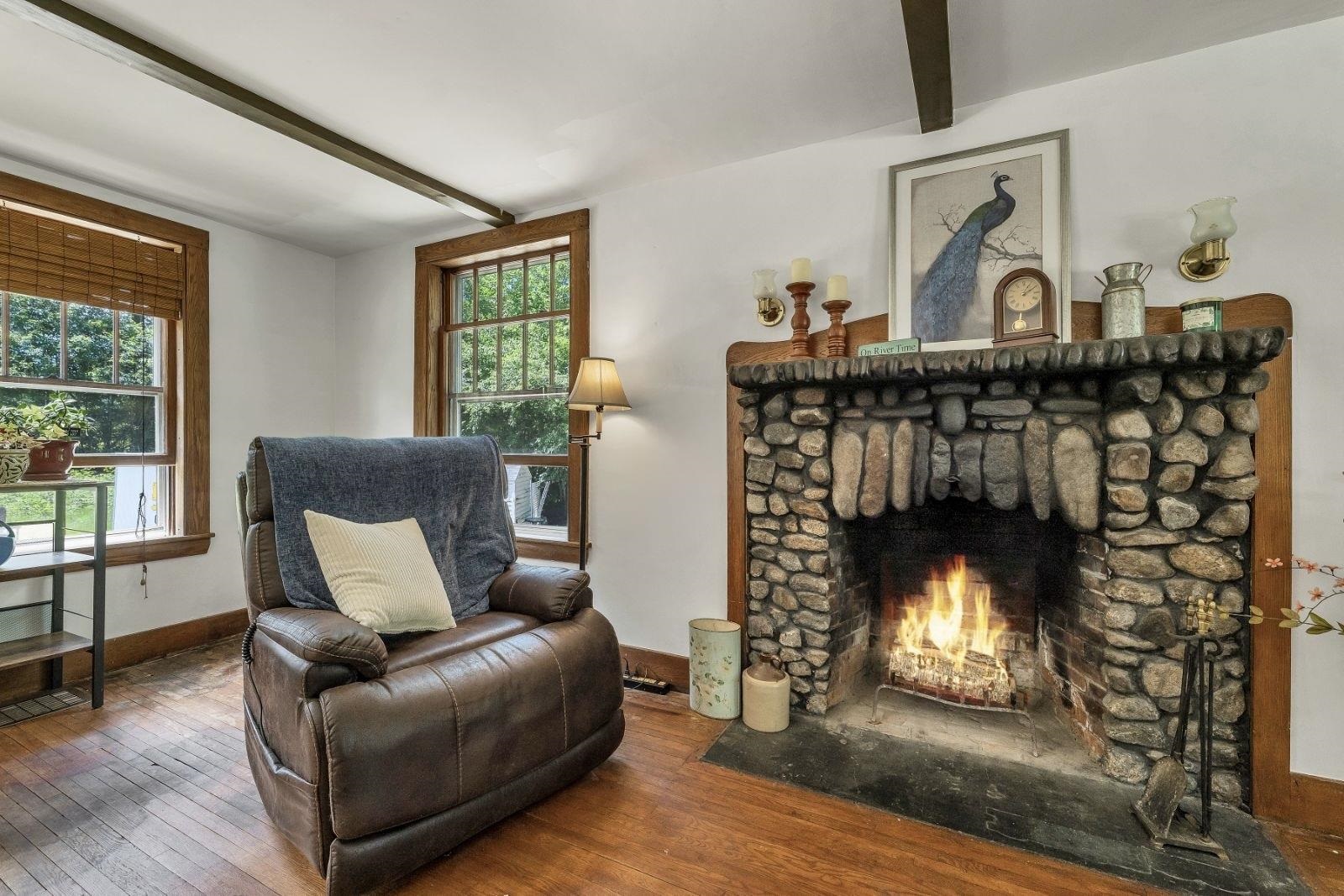 Living room with a towering stone fireplace, burning fire, and leather recliner.