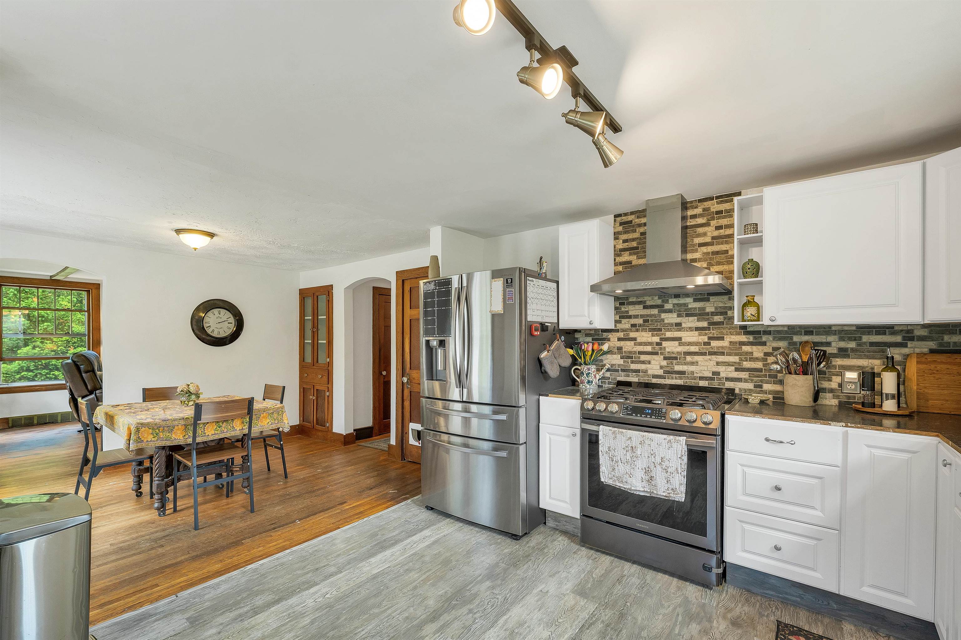 Kitchen with stainless steel appliances, brick-pattern backsplash, and adjoining dining table.