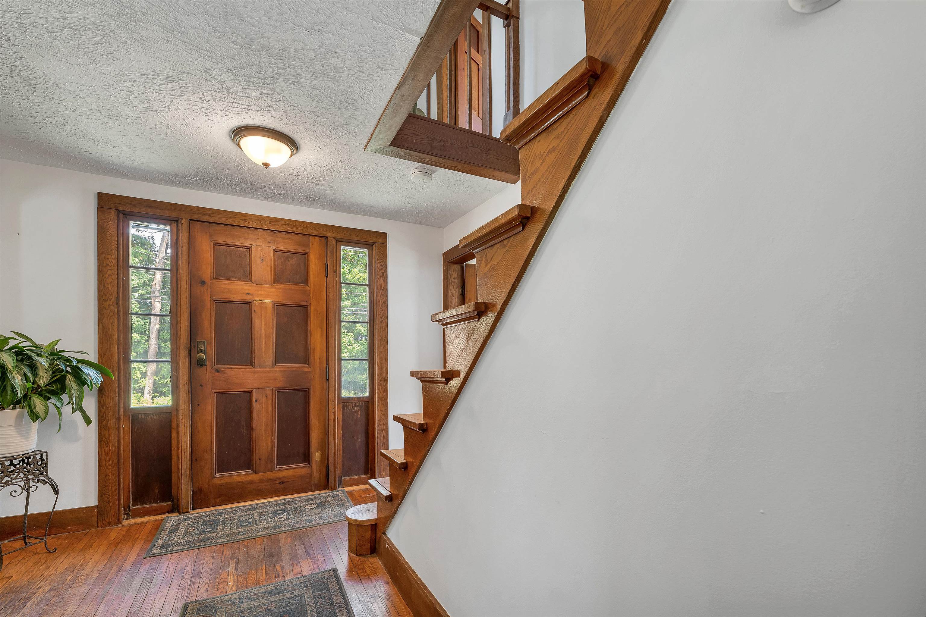 Entry foyer with a paneled wood front door, hardwood floors, and a staircase.