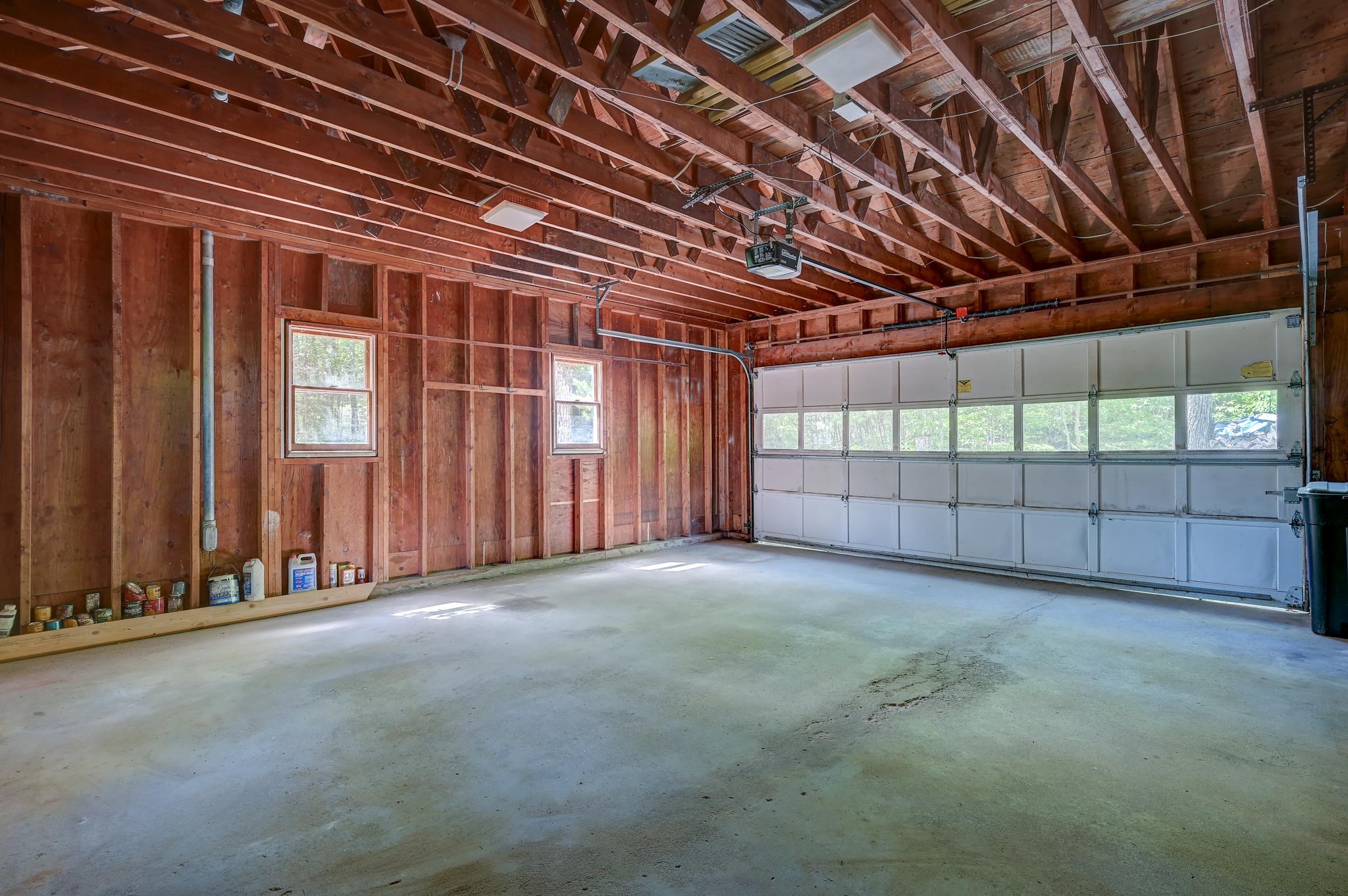 Spacious garage with exposed timber framing, concrete floor, and a windowed overhead door.
