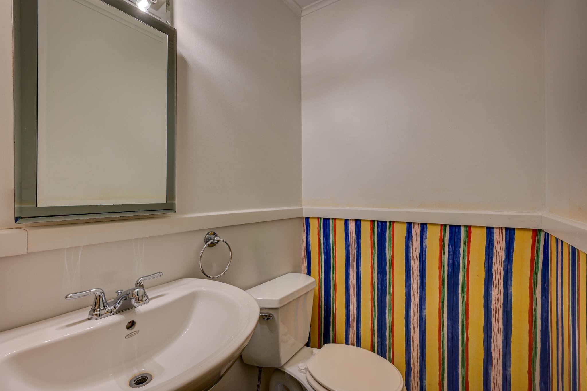 Bathroom with a white vanity sink and a colorful striped shower curtain.
