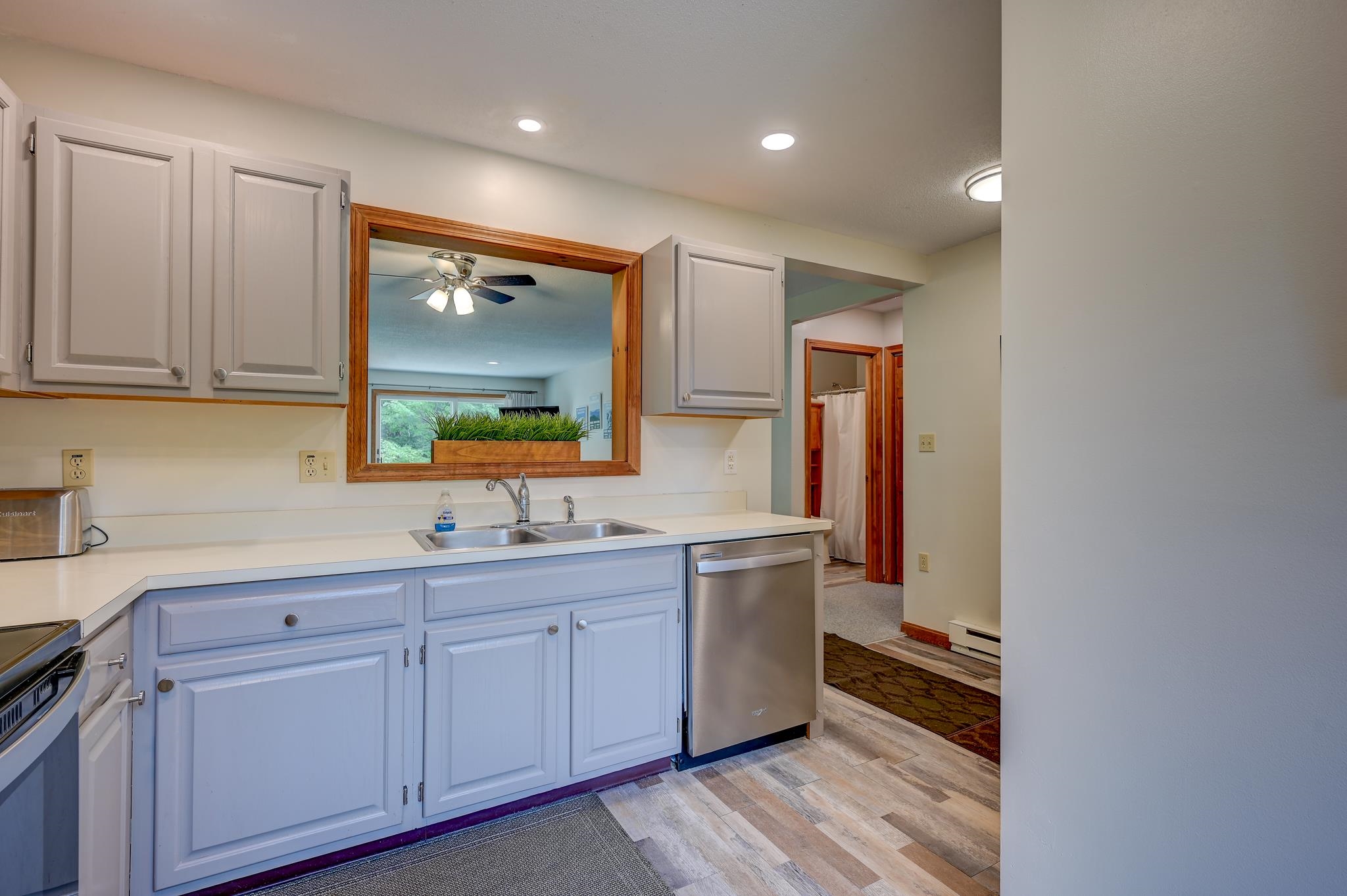 Kitchen with pale blue cabinets, a double sink, stainless dishwasher, and a wood-framed opening to the living area.