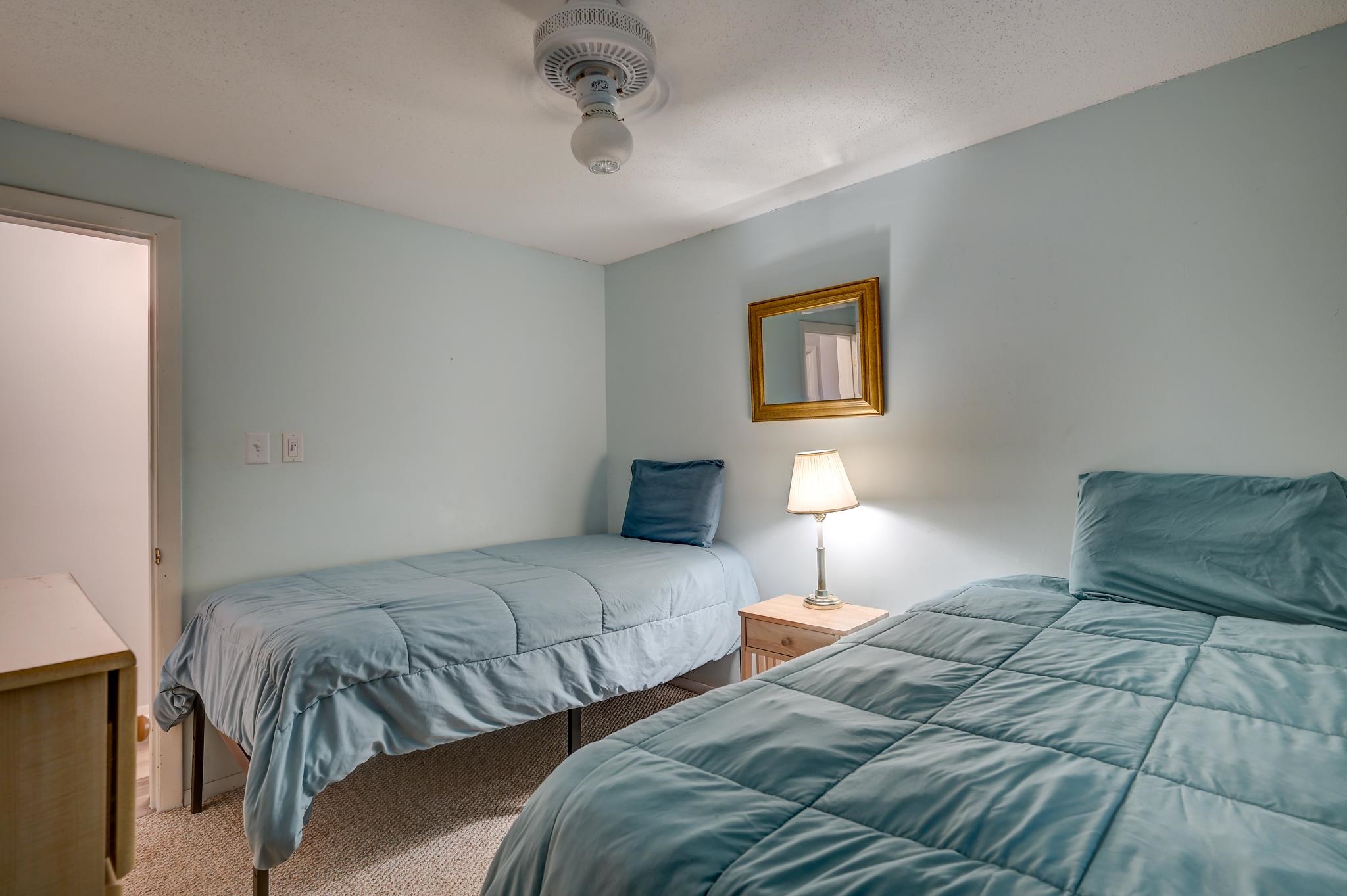 Bedroom with two blue-covered single beds and a lamp between them.