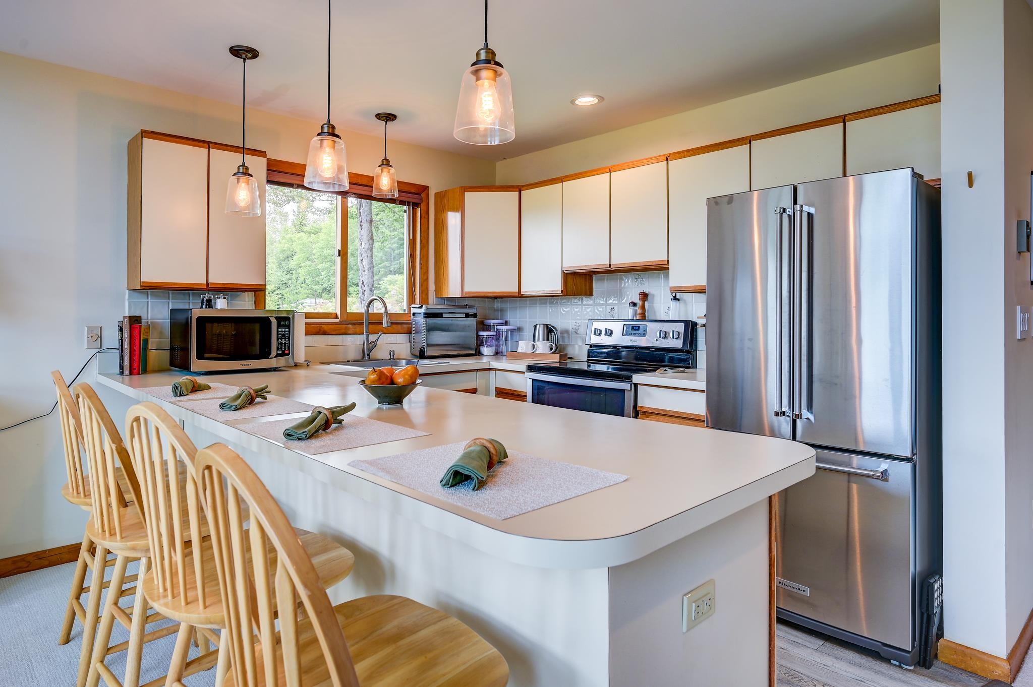 Kitchen with a large breakfast island, wooden stools, and stainless steel appliances.