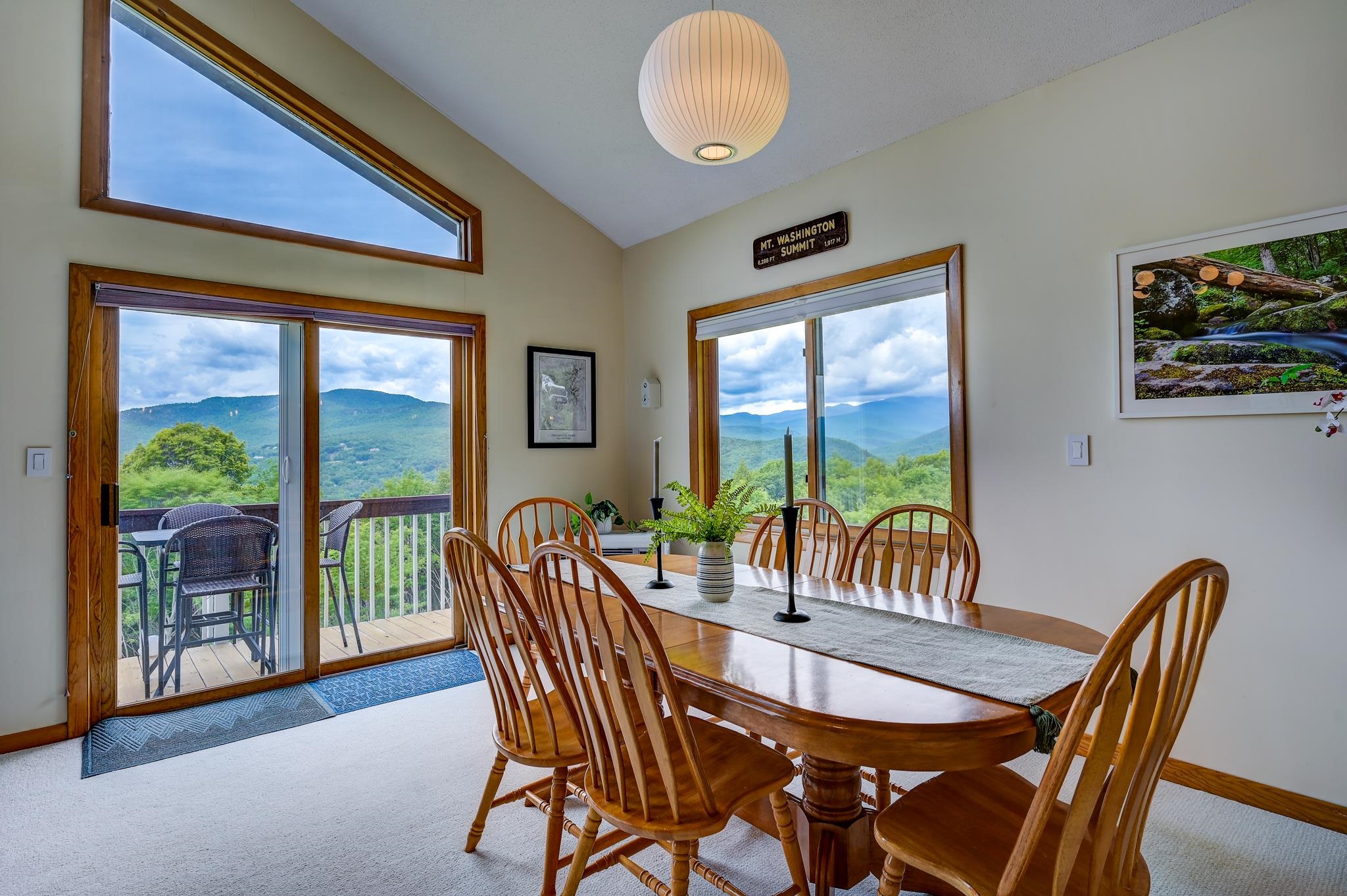 Dining room with a wooden table and mountain views through large windows.