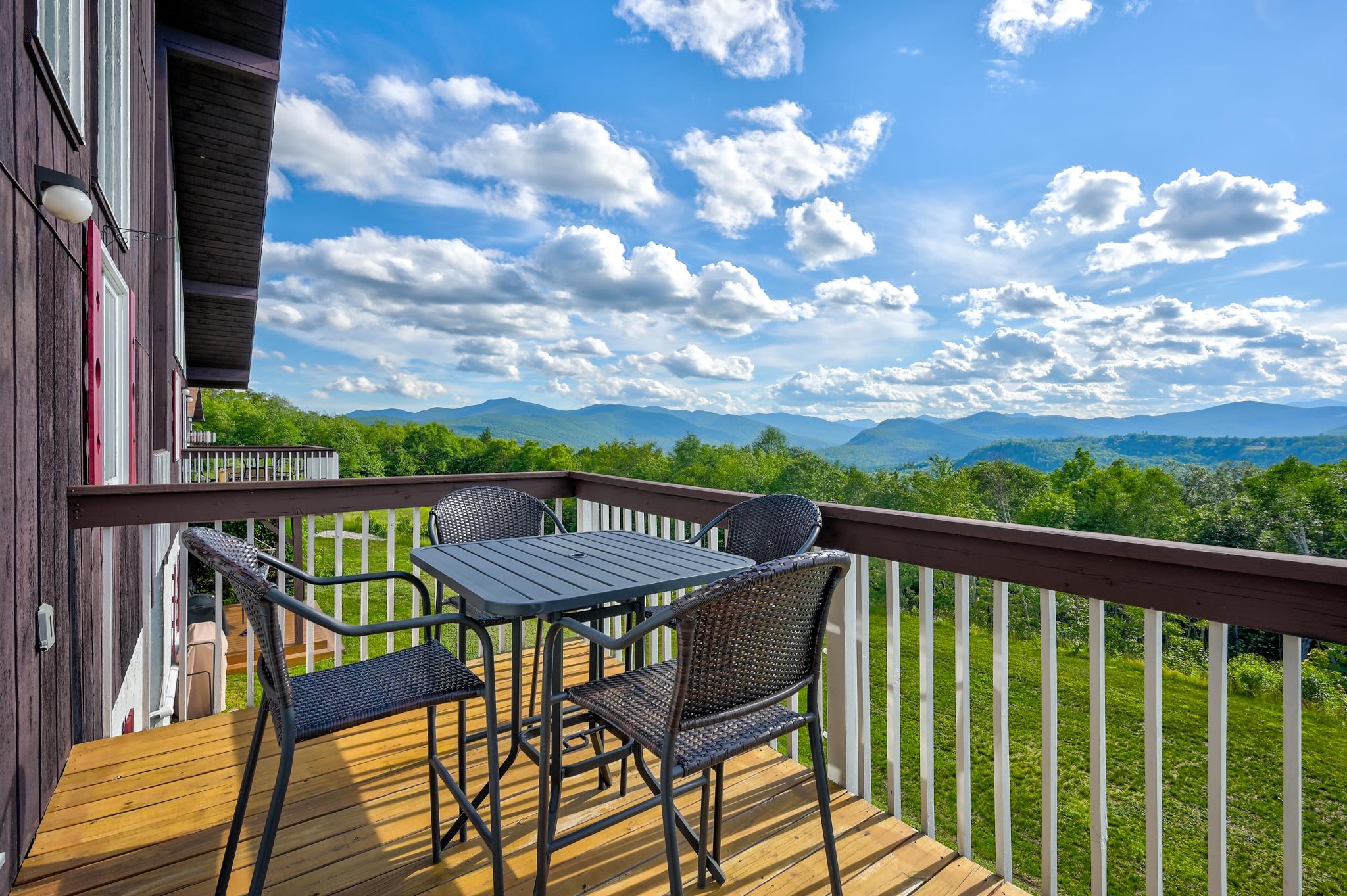 Deck with patio table and chairs overlooking a wide mountain view.