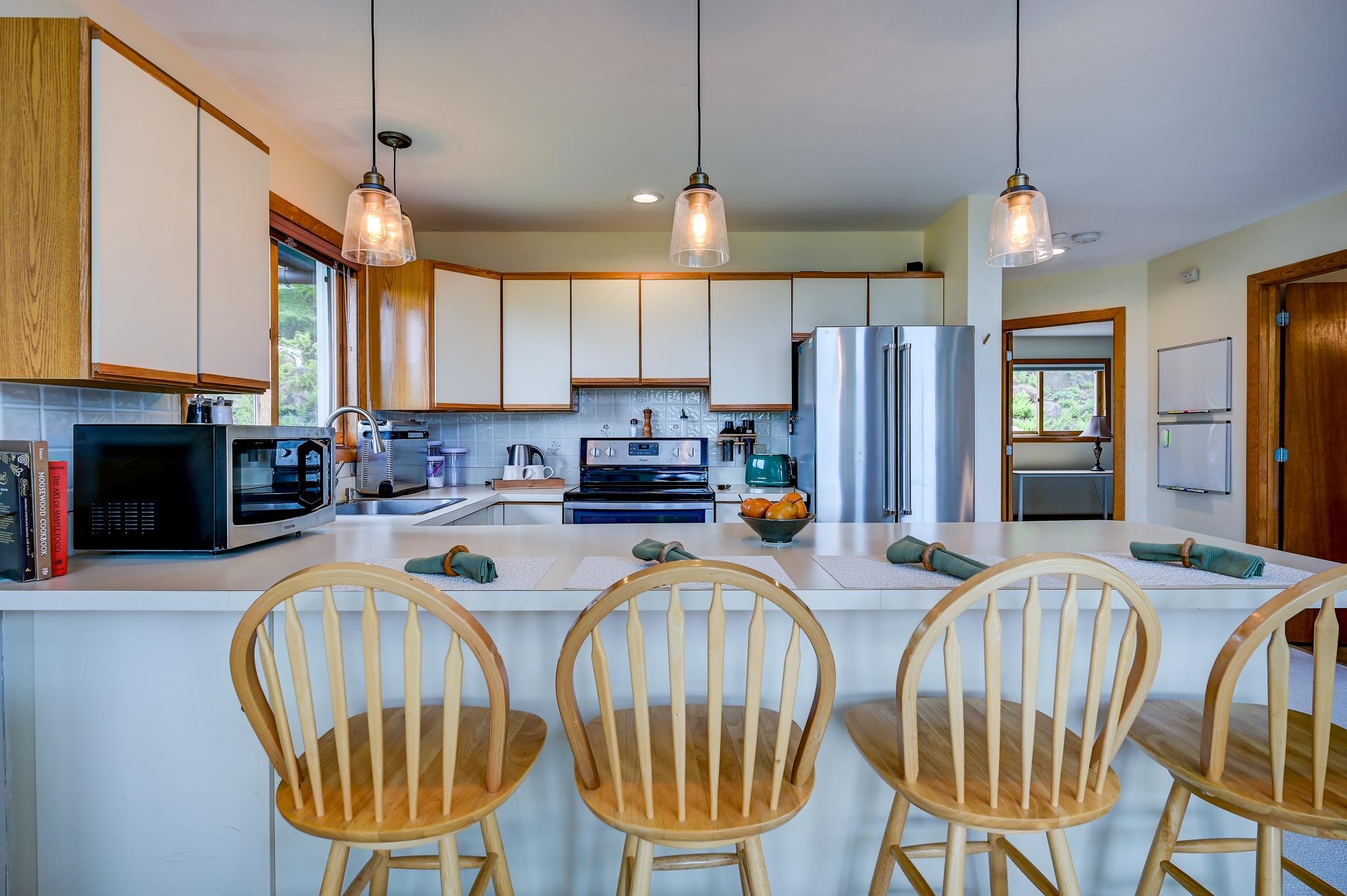 Kitchen with a wide breakfast bar, wooden chairs, wood-trimmed cabinets, and stainless steel appliances.