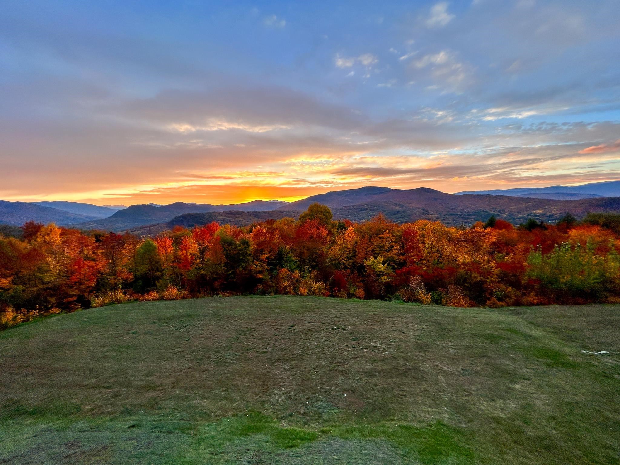 Autumn mountain views at sunset beyond a grassy hillside.