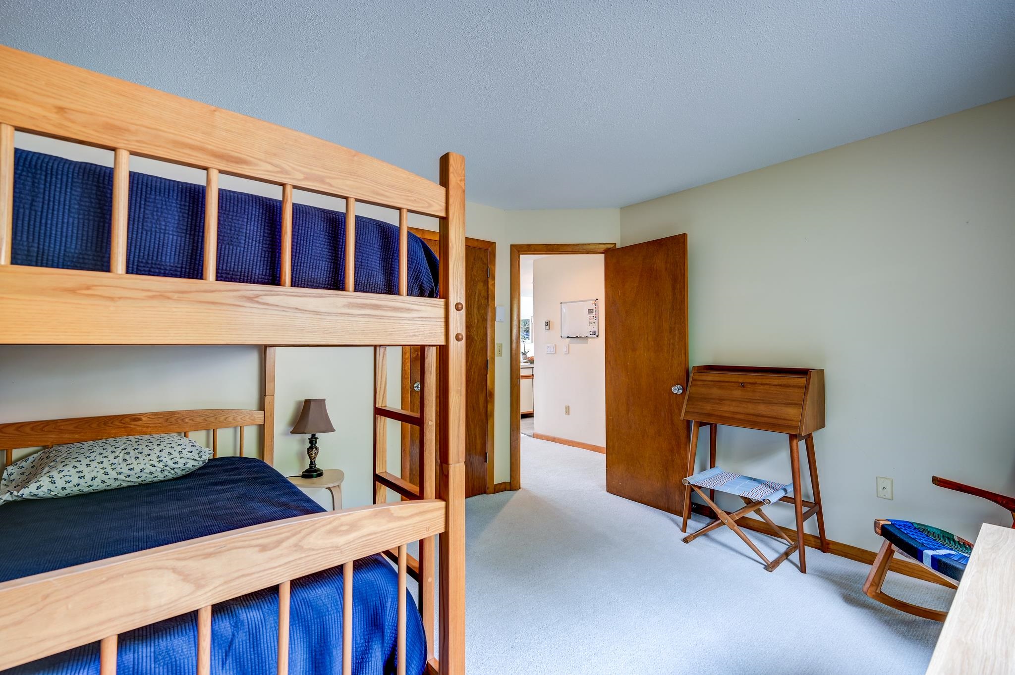 Bedroom with a wooden bunk bed, blue bedding, and a small writing desk.