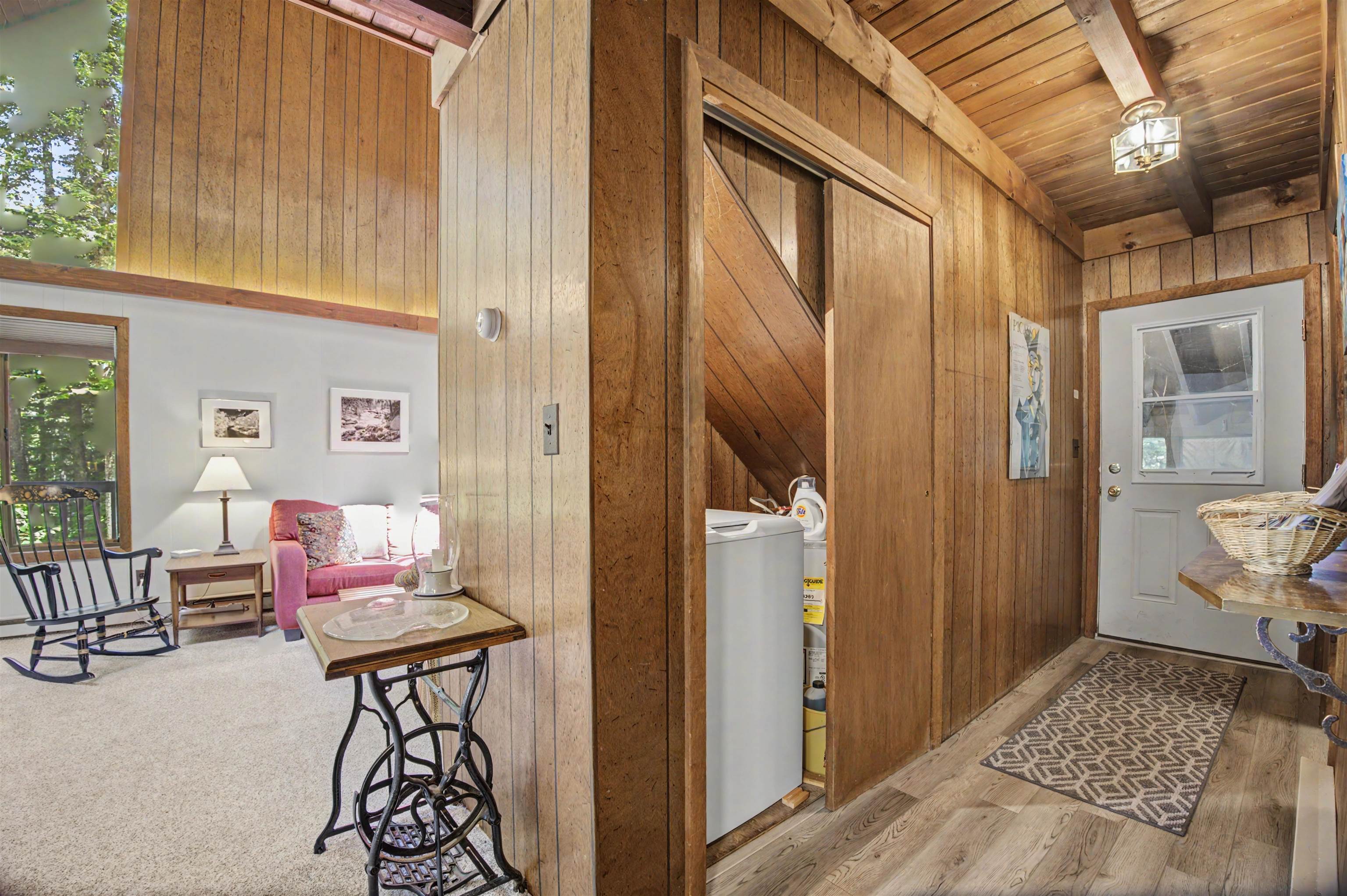 Wood-paneled entryway with a sliding barn door, laundry area, and adjoining sitting room.