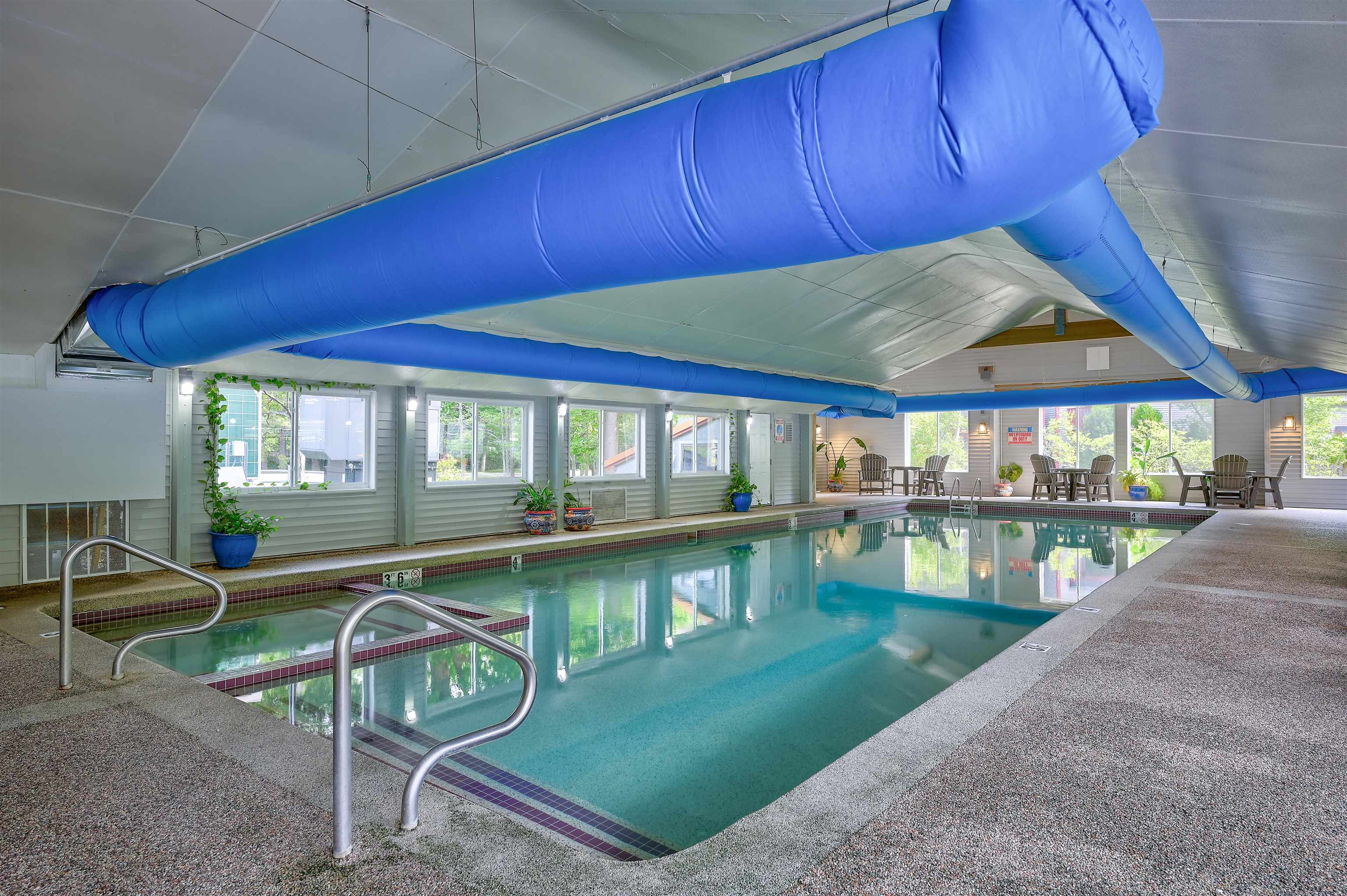 Indoor pool with turquoise water, metal entry rails, and a large blue ceiling duct.