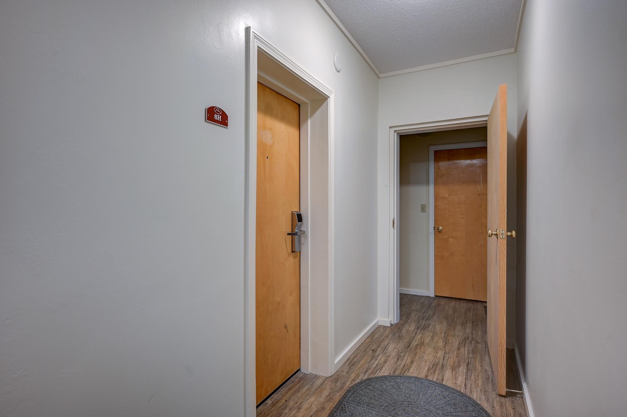 Entry hallway with a wood entrance door, electronic lock, and round gray rug.