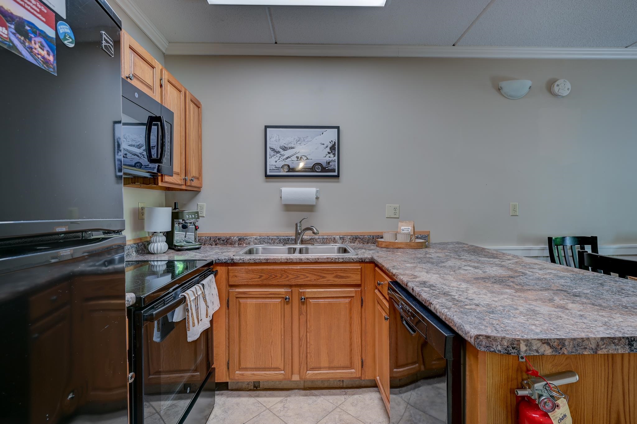 Kitchen with warm wood cabinets, a wide breakfast bar, and black appliances.