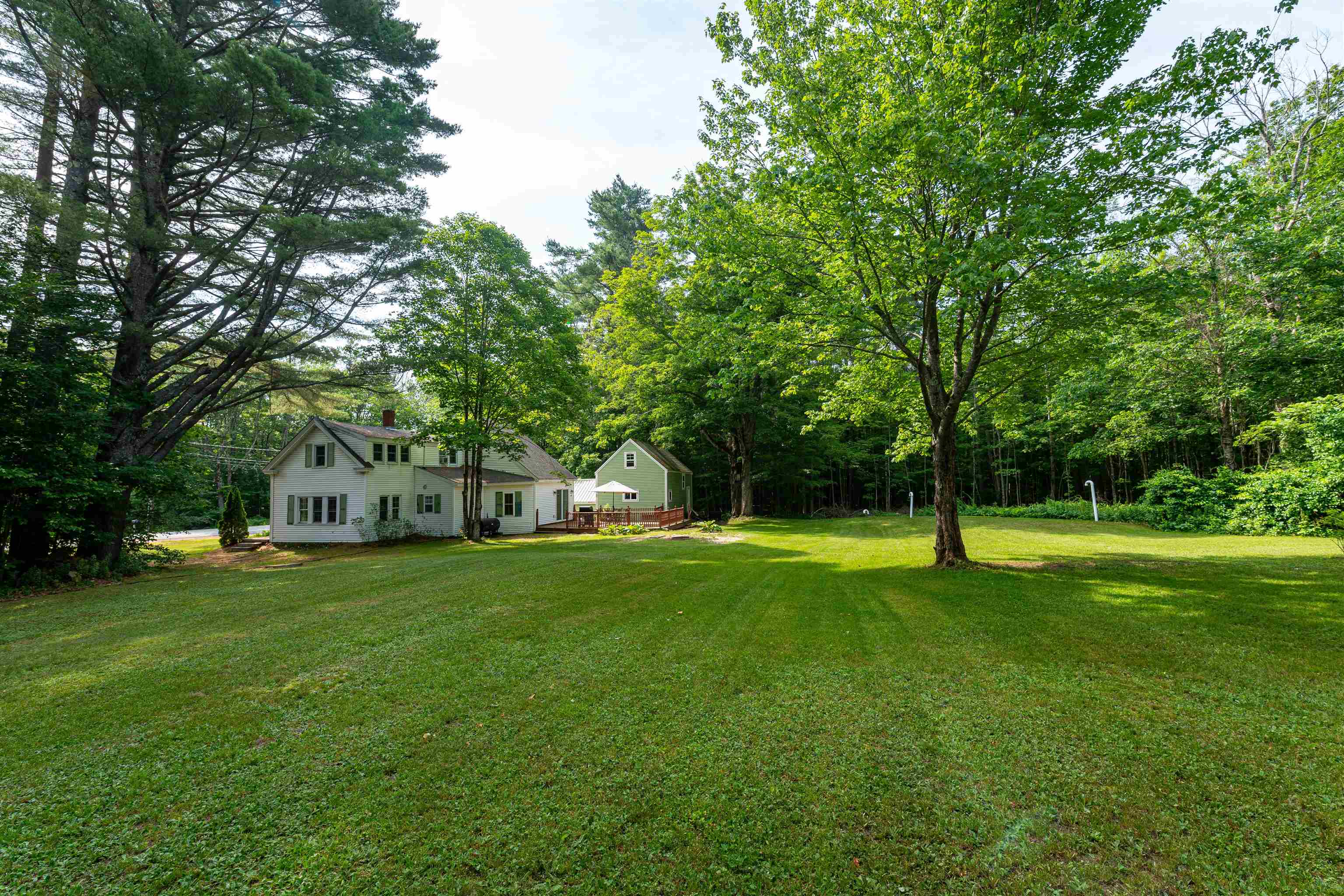 House and separate outbuilding beyond a broad, tree-lined lawn
