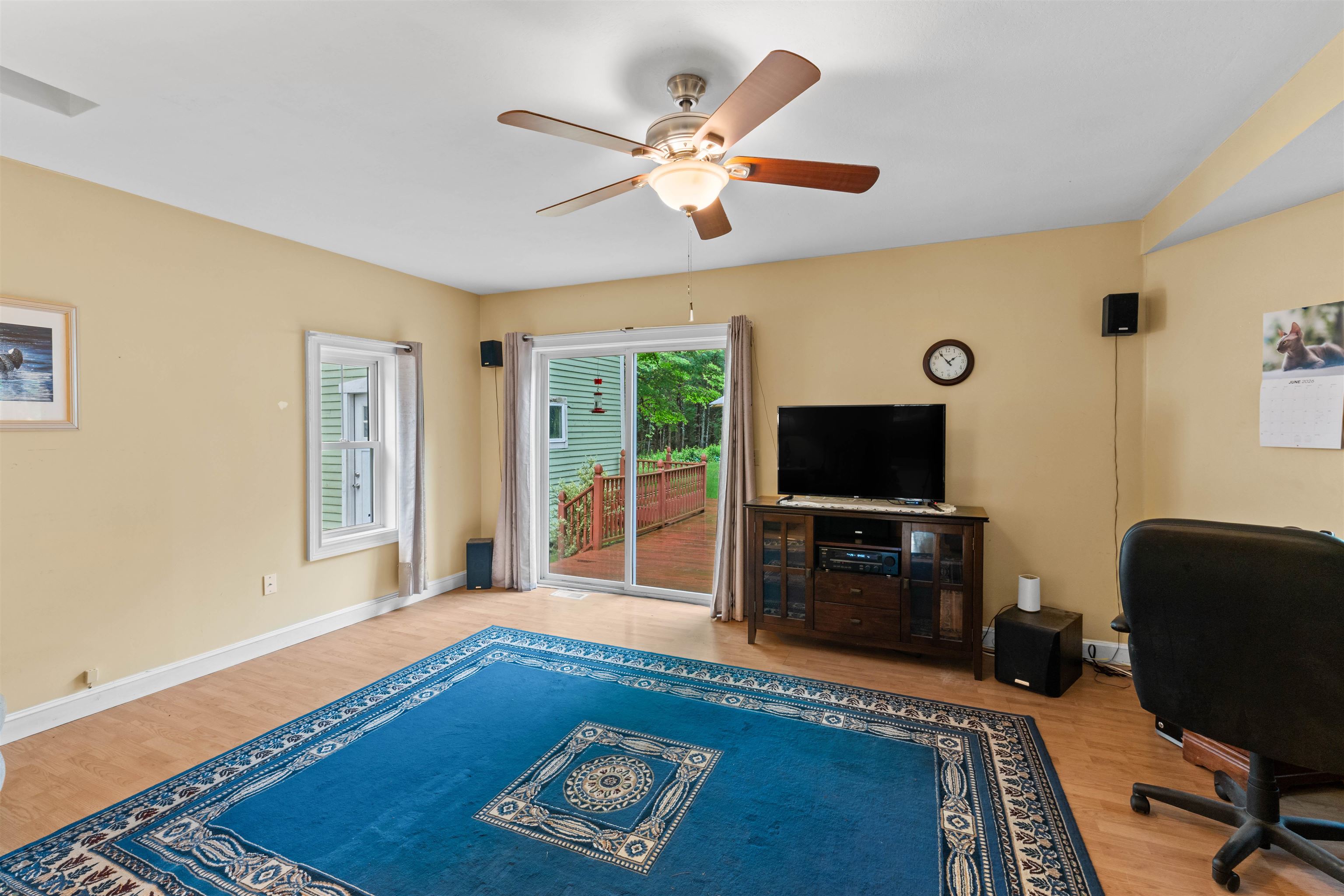 Living room with a blue patterned rug, ceiling fan, and sliding doors to a deck.