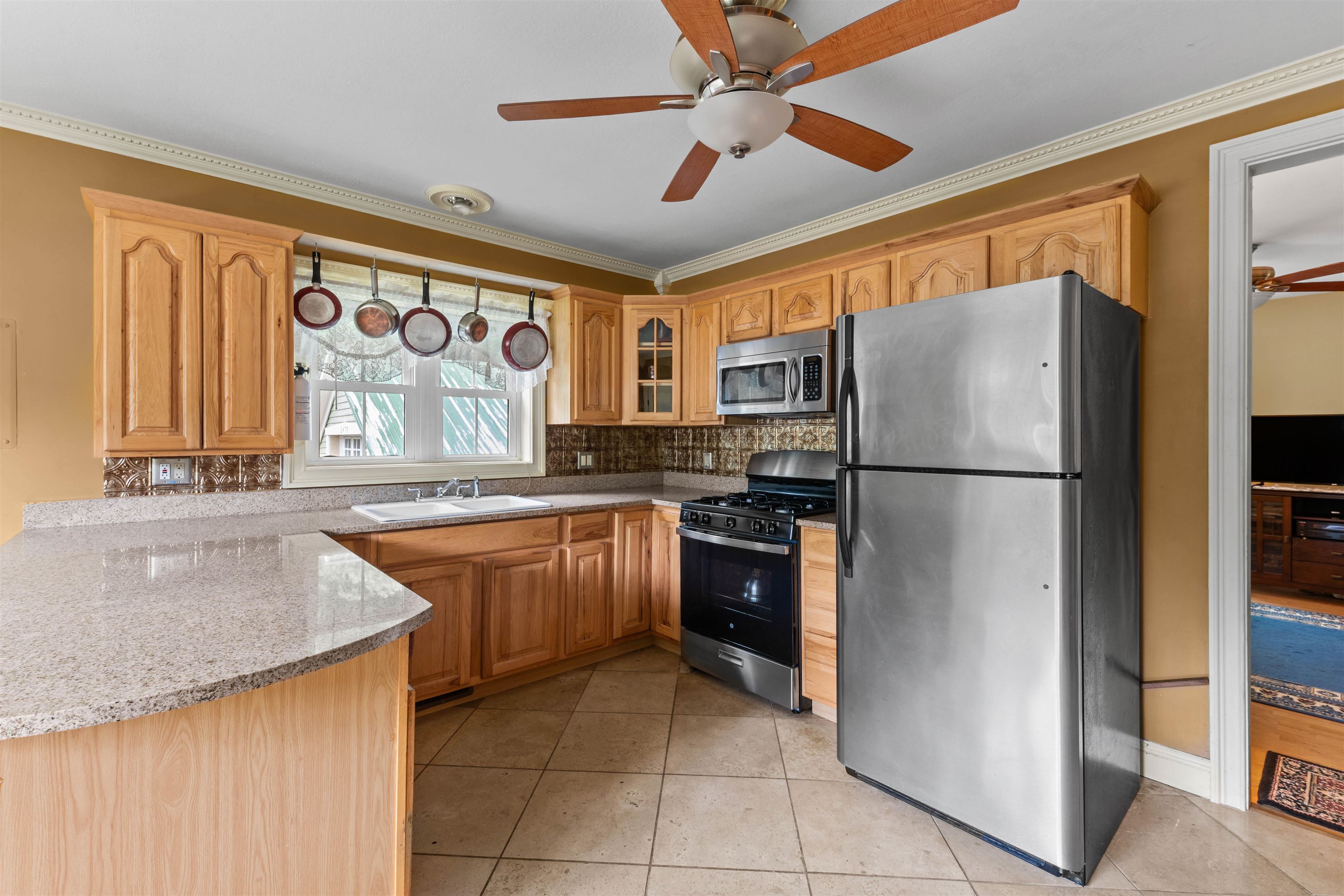 Kitchen with light wood cabinets, granite countertops, and stainless steel appliances.