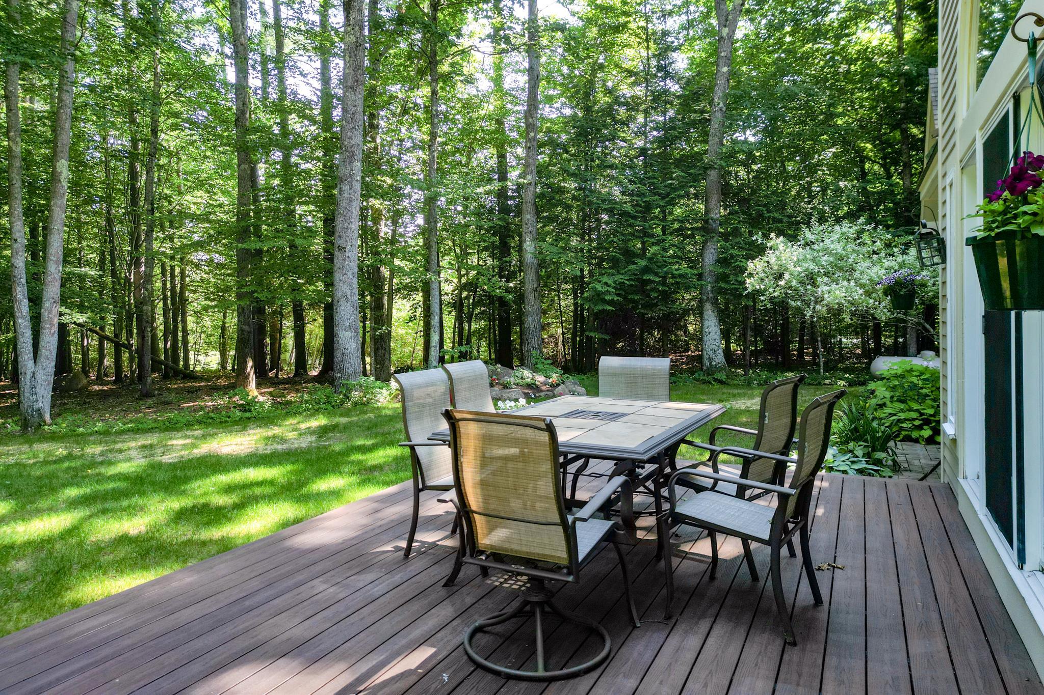 Wooden deck with a dining set beside a wooded backyard.