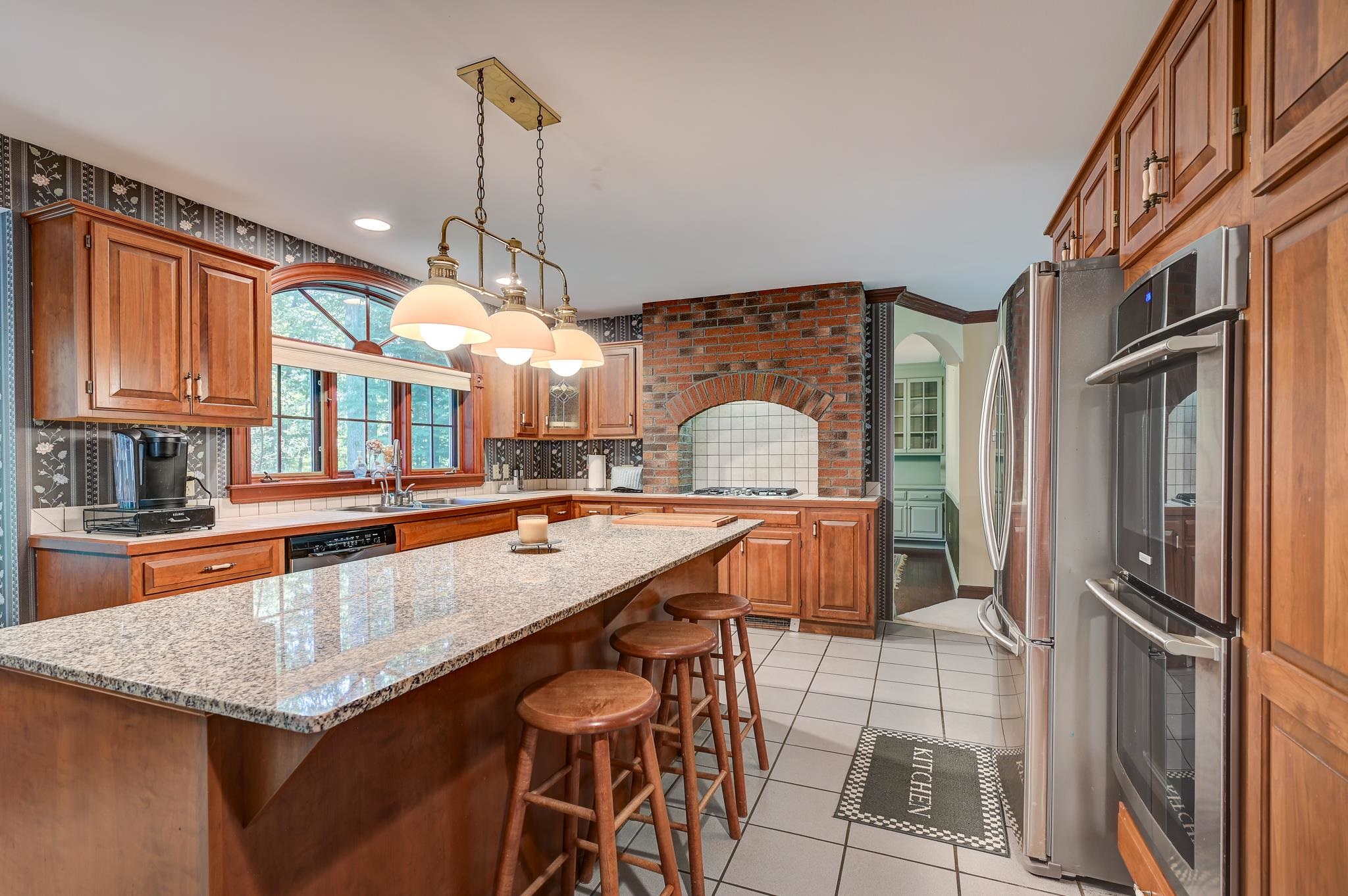 Kitchen with a granite island, cherry cabinets, and a brick cooking alcove.