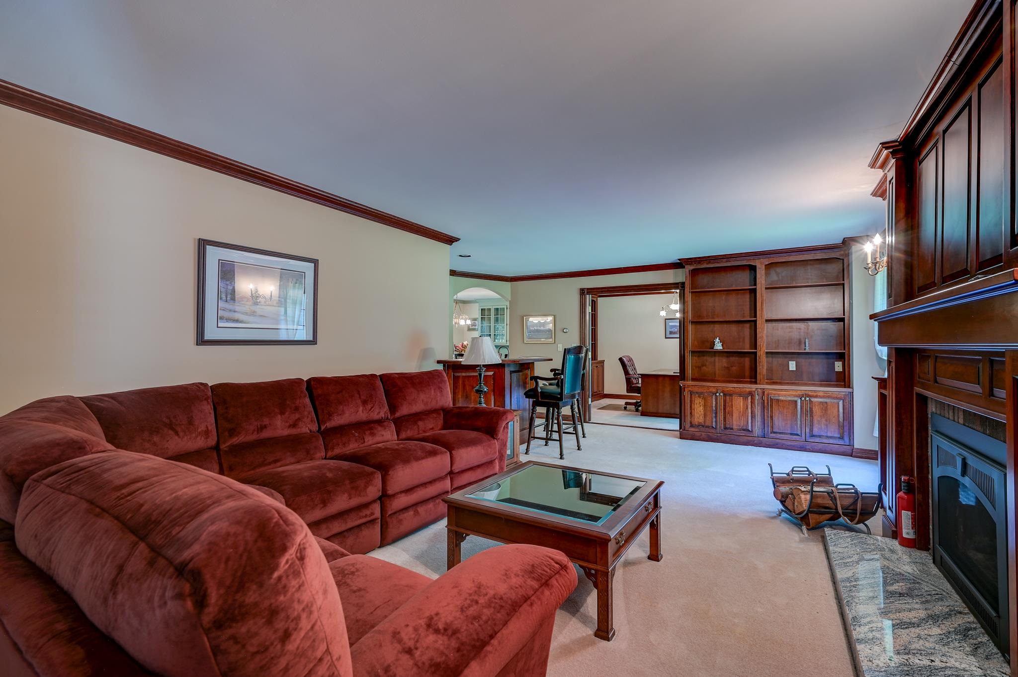 Living room with a red sectional sofa, built-in wood shelving, and a fireplace.