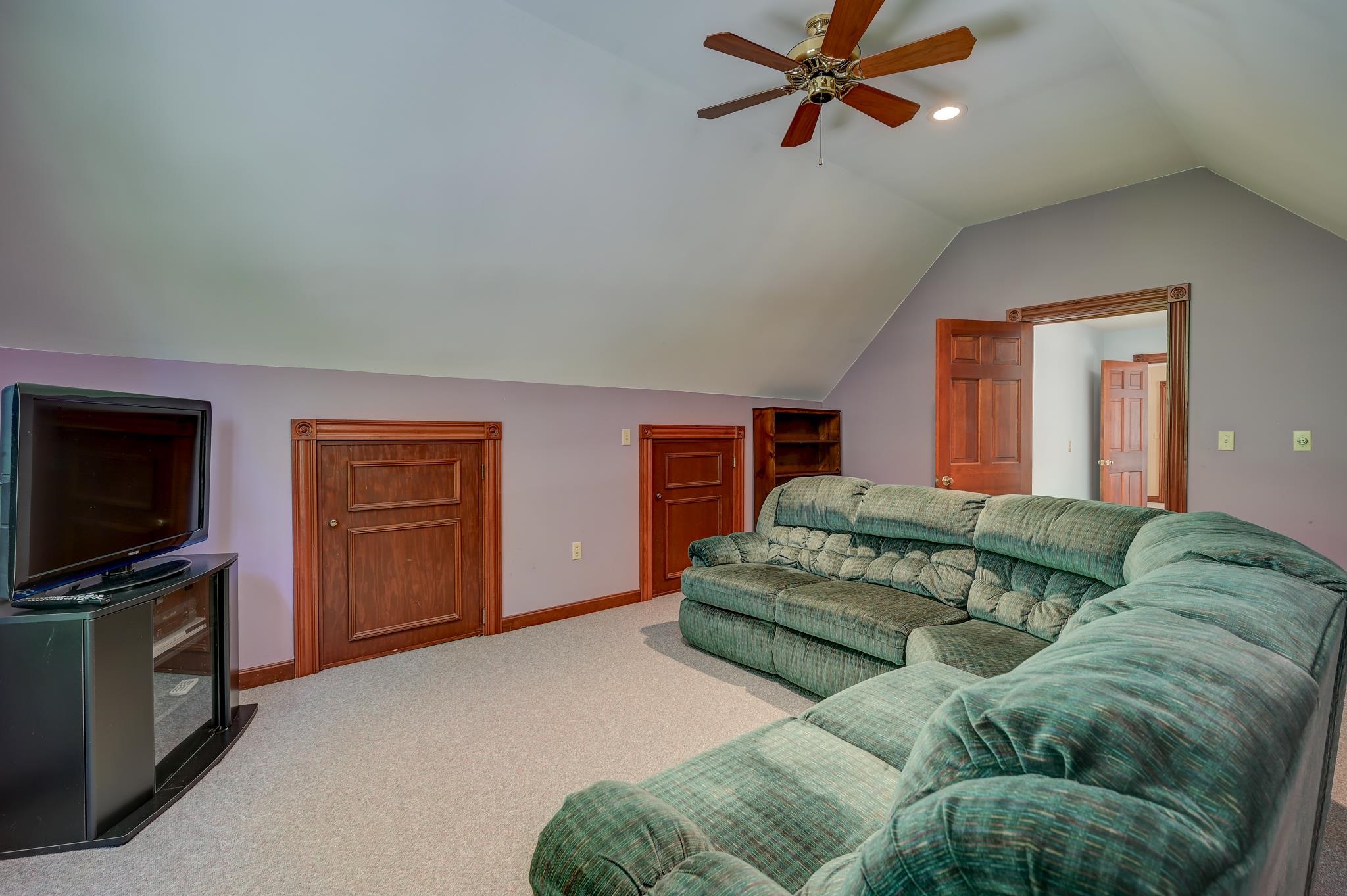 Furnished media room with a large sectional sofa, television, and wood-trimmed doors.