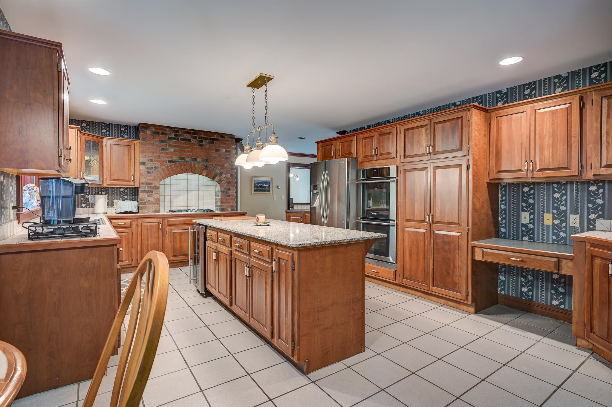 Kitchen with a large wood island, extensive cabinetry, and a brick cooking alcove.
