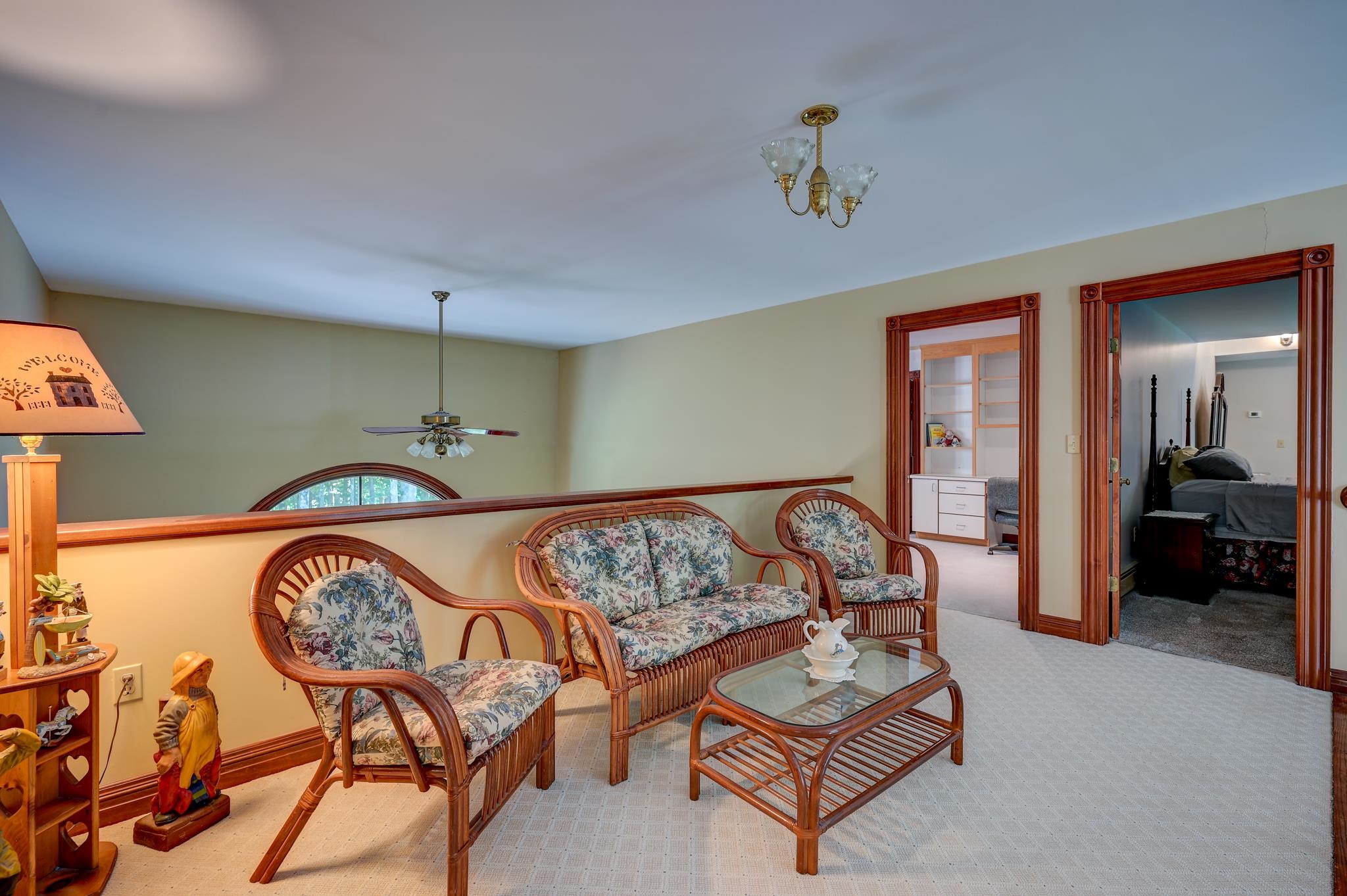Upstairs sitting area with wicker floral seating, glass coffee table, and adjoining bedrooms.