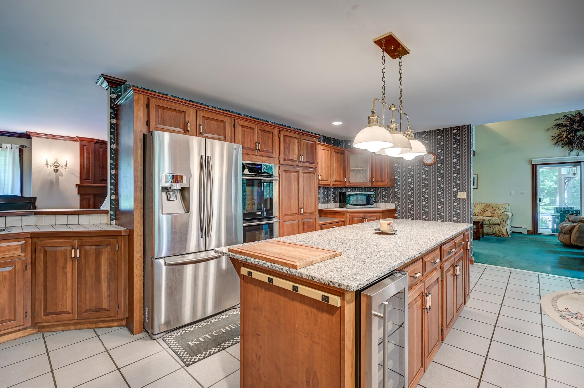 Kitchen with a large granite island, cherry cabinets, and stainless steel appliances.