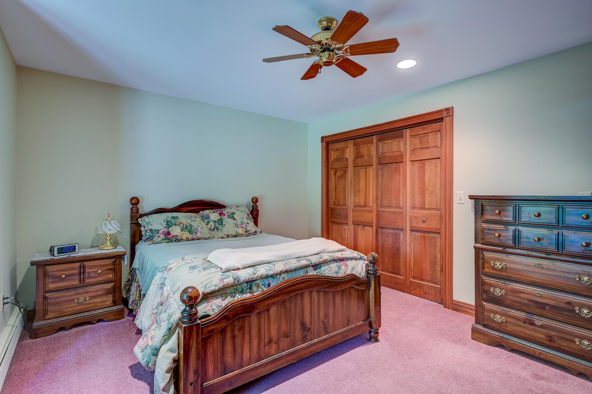 Furnished bedroom with a carved wooden bed, floral bedding, and matching wooden dressers.
