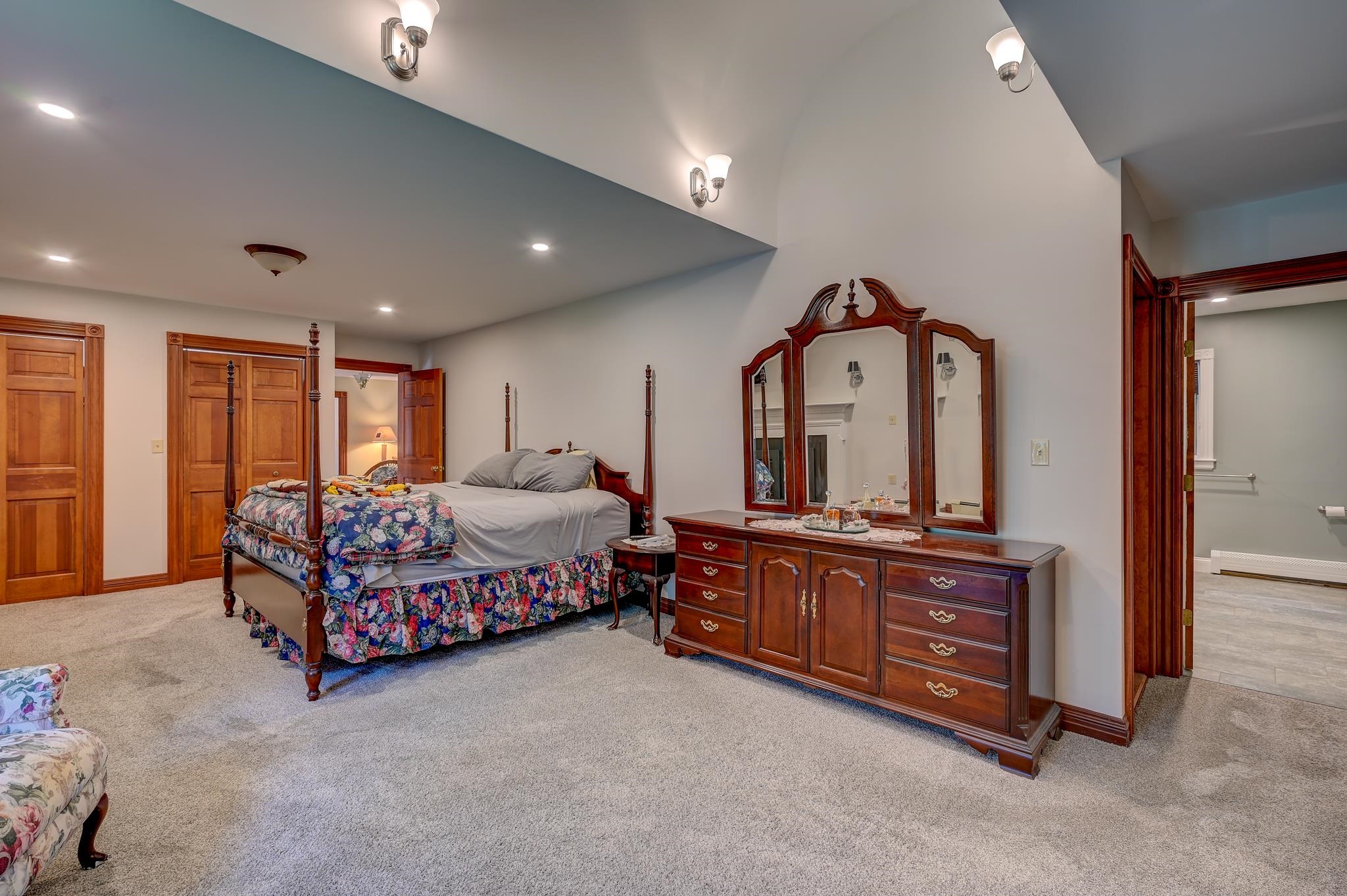 Bedroom with a four-poster bed, carved wood dresser, and adjoining bathroom.
