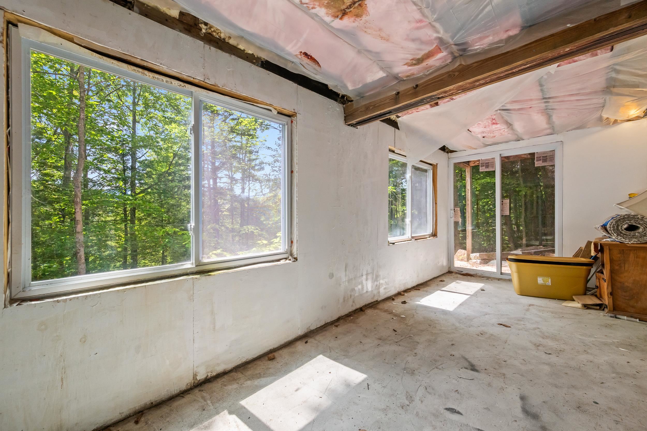 Unfinished room with large windows, sliding glass doors, and exposed ceiling insulation.