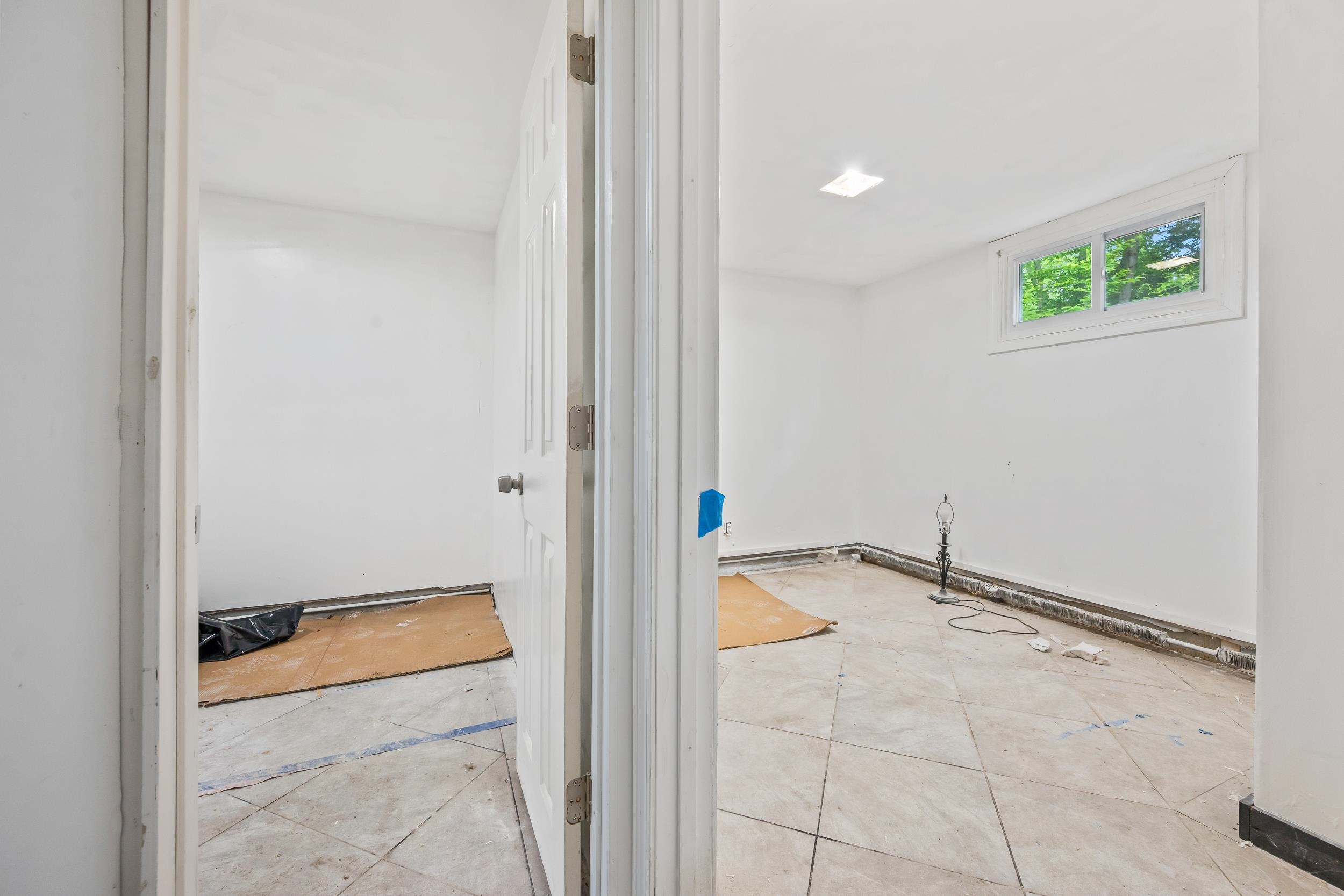 Two empty rooms under renovation, with tiled floors, unfinished baseboards, and high windows.