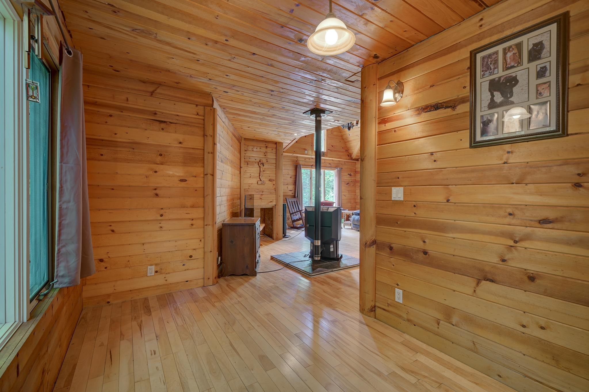 Wood-paneled living room with a central wood stove and wide-plank floors.