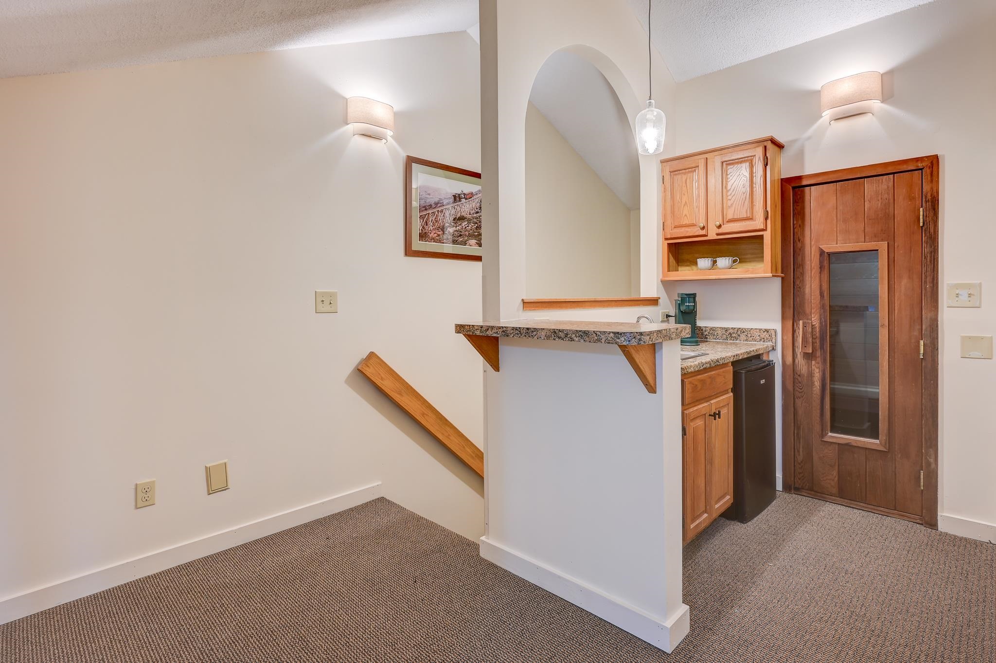 Compact kitchenette with wood cabinets, granite counters, and a wooden glass-panel door.