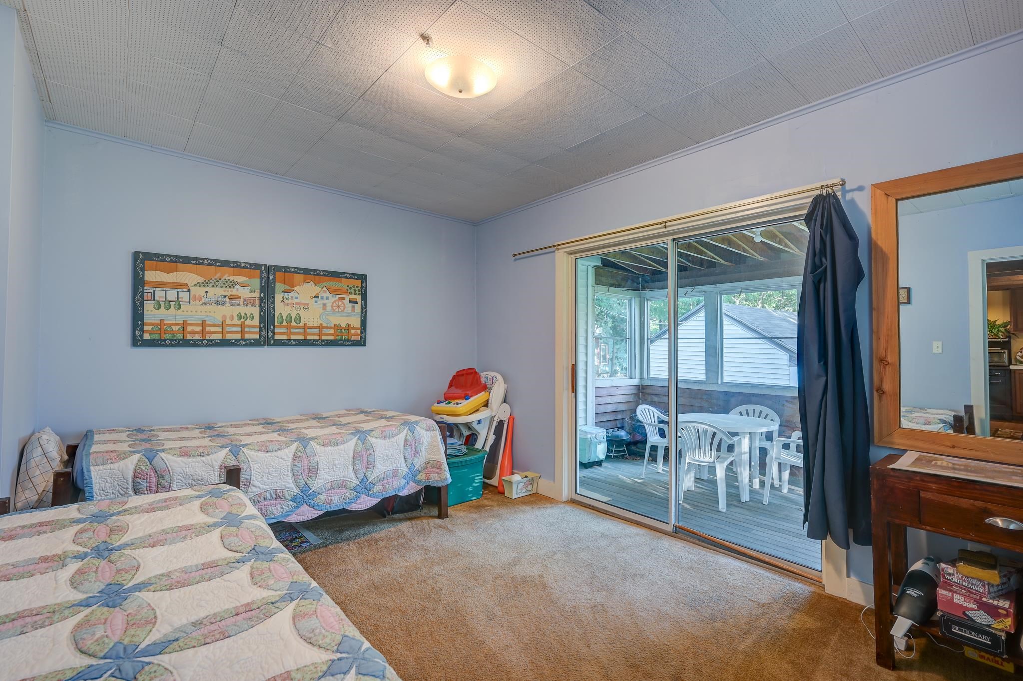 Bedroom with patterned quilts and sliding glass doors opening onto a covered porch.