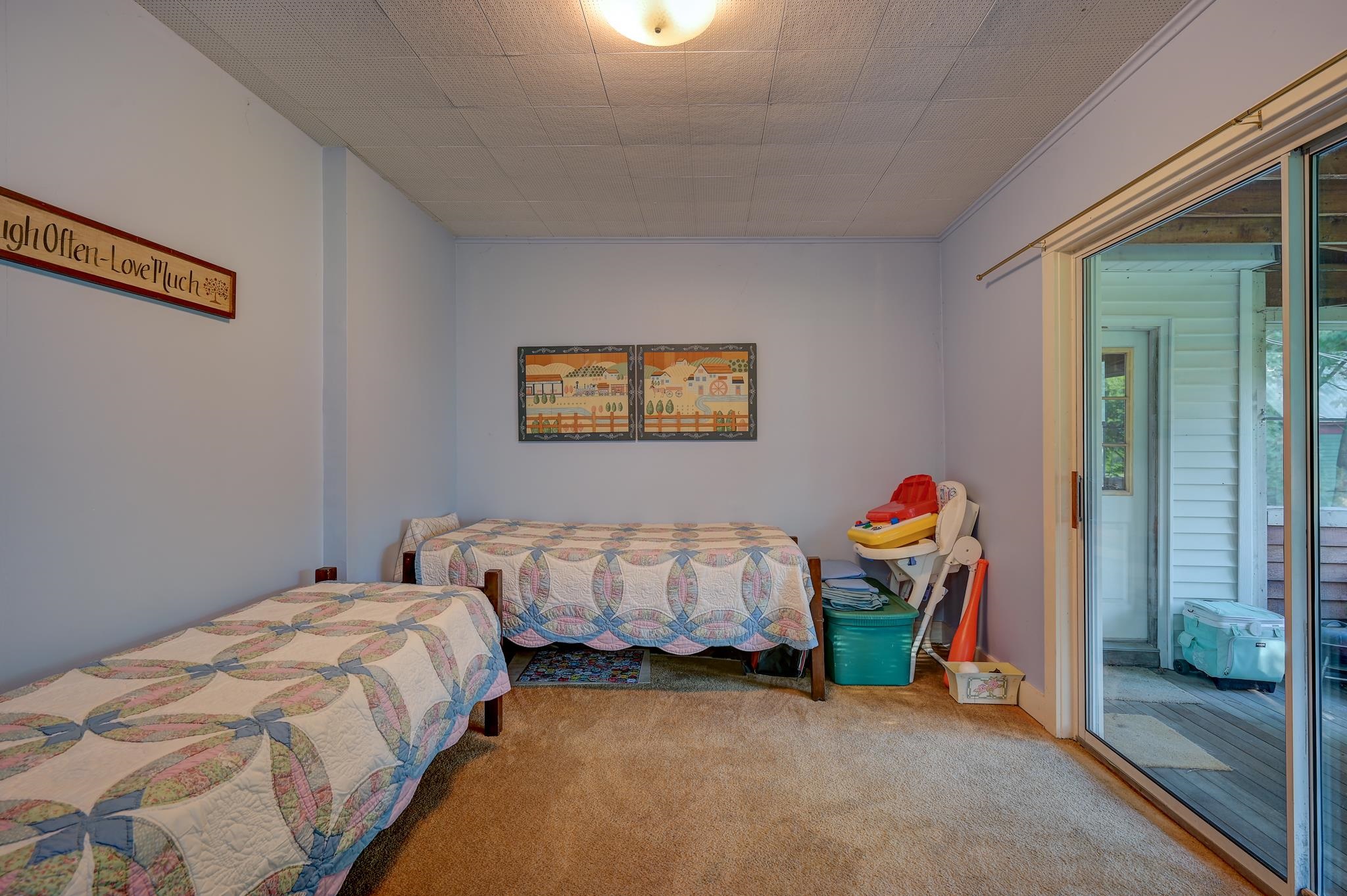 Bedroom with two quilt-covered single beds and a sliding glass door to the porch.