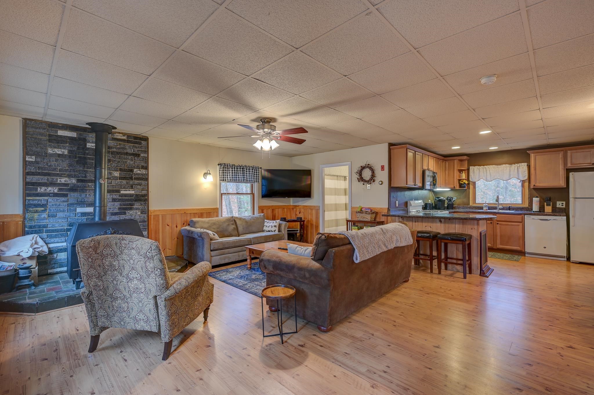 Open-plan living room and kitchen with a brick fireplace, wood stove, and kitchen island.